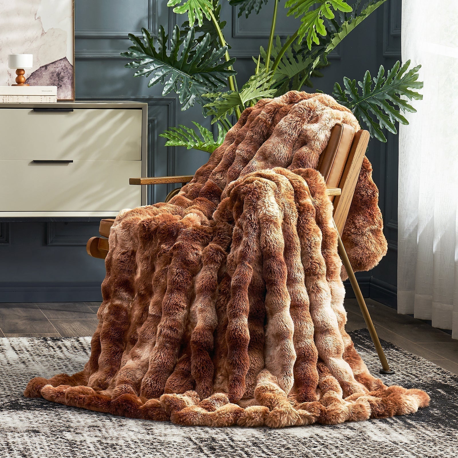 A brown, textured Cozy Bliss blanket draped over a wooden chair in a room.