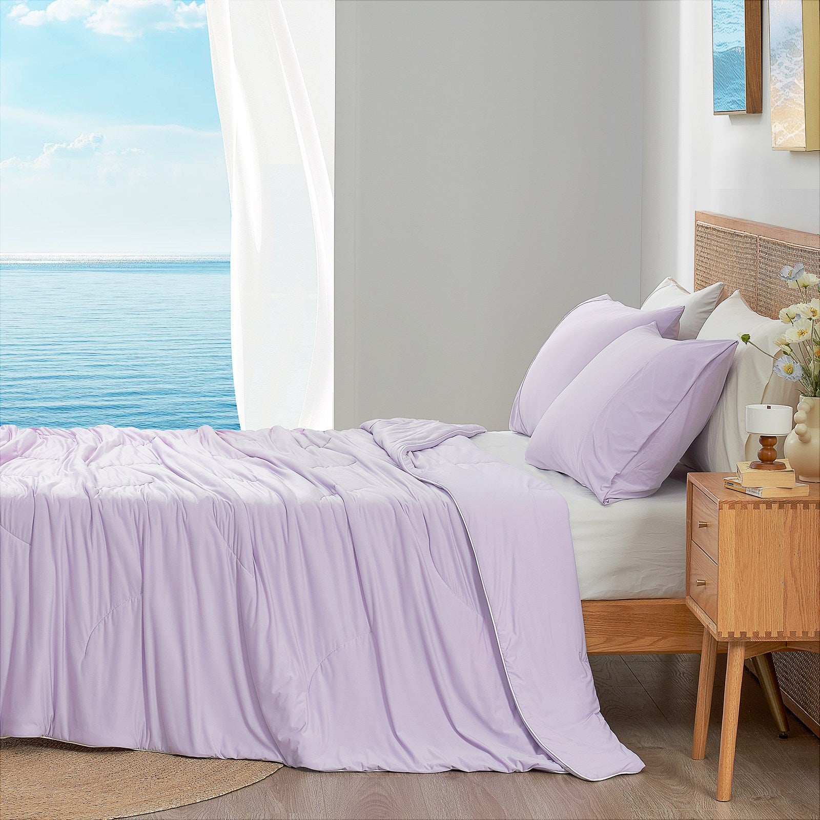 Lavender purple cooling comforter on bed side view with sea, offering breathable bedding for a cozy sleep. #color_Lavender Purple