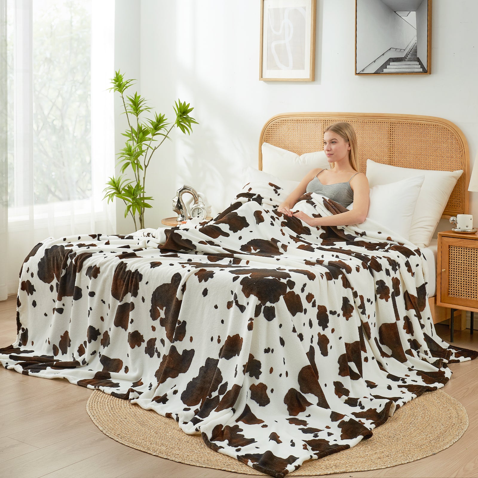 Woman sitting on a bed with a cow print blanket in a bright bedroom. #color_Black Brown