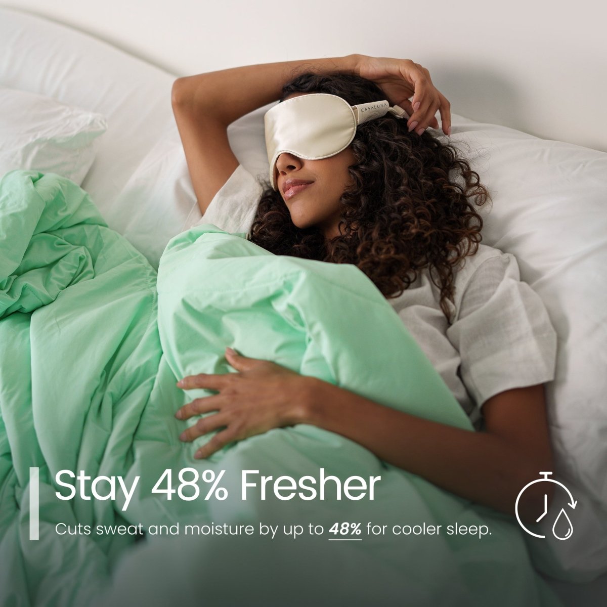 Woman lying in bed with a cooling comforter on, surrounded by green bedding.#color_Mint Macaron