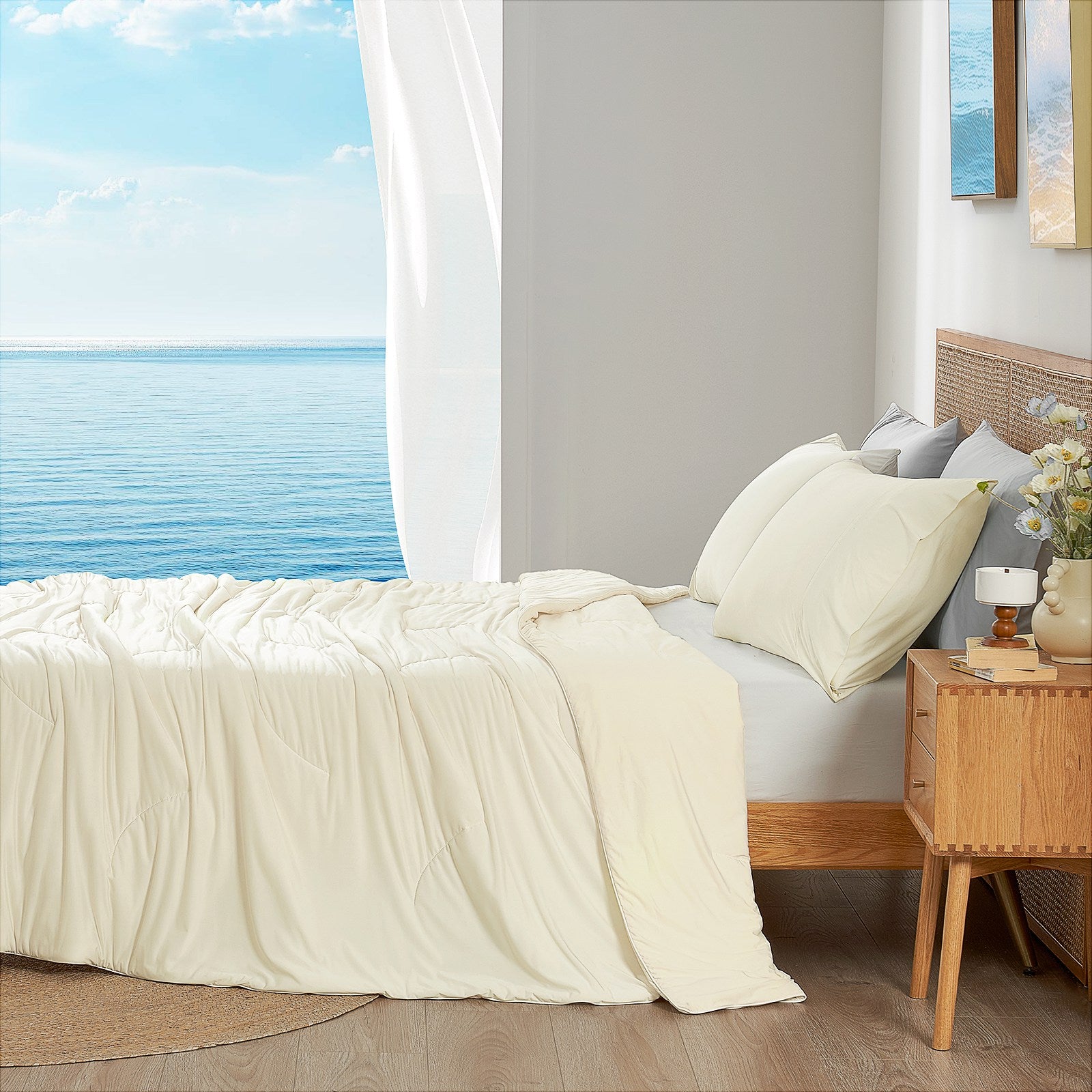 Snow ivory cooling comforter on bed side view with sea, offering breathable bedding for a cozy sleep. #color_Snow Ivory