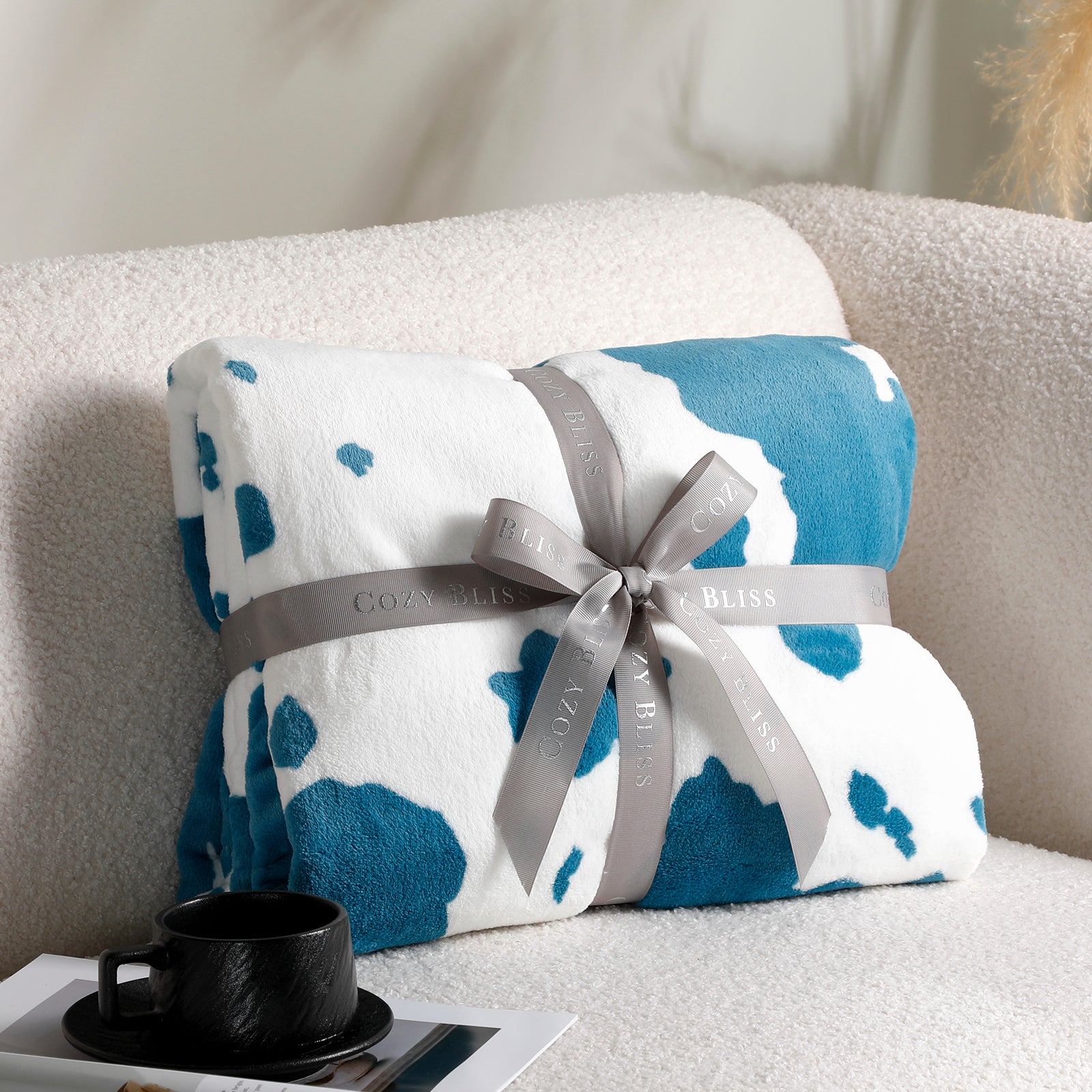 Folded blanket with blue and white pattern and gray ribbon on a couch #color_Blue