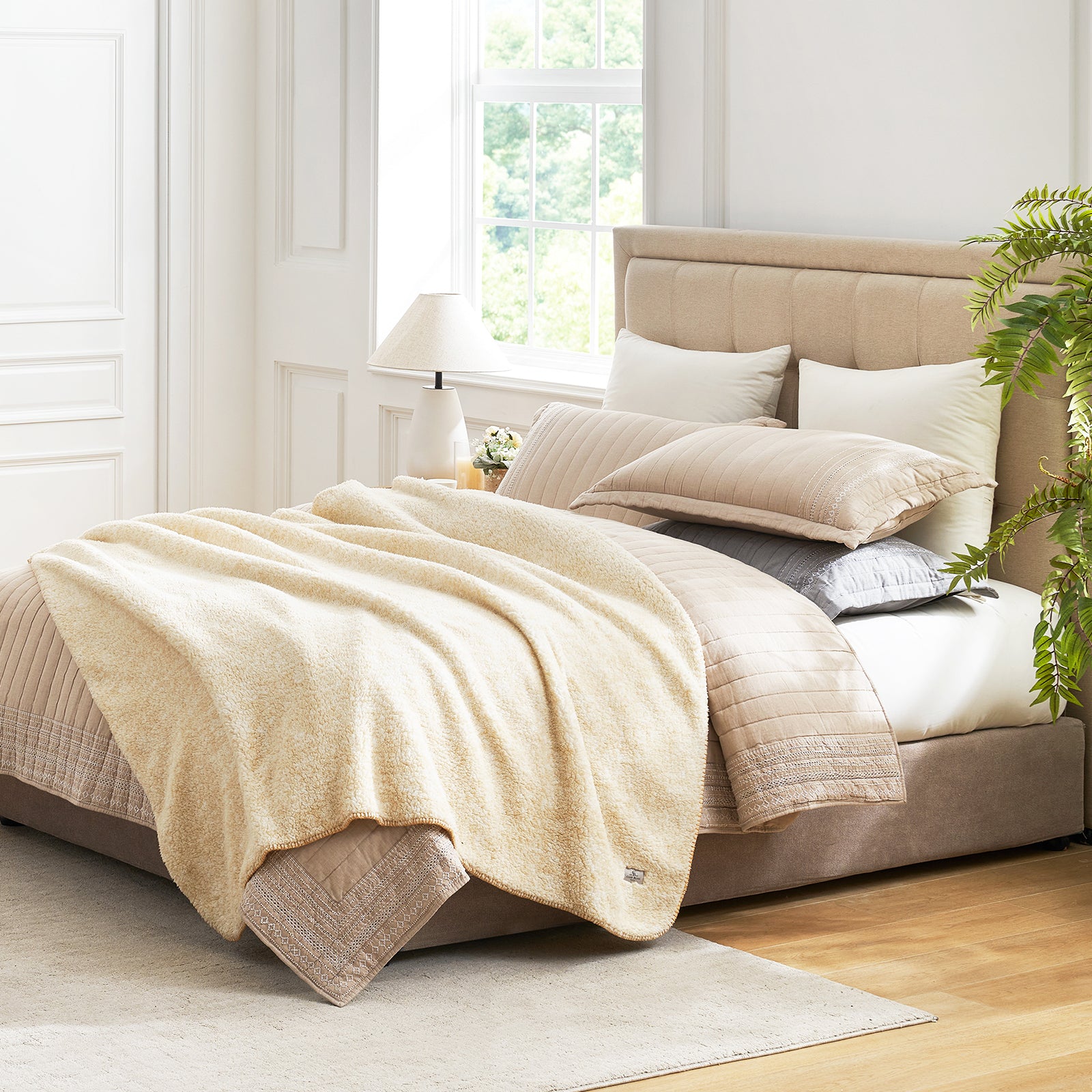 Cozy Bliss beige Sherpa throw blanket on a bed. Soft, breathable blanket for cozy comfort and style. #color_ Mottled Beige