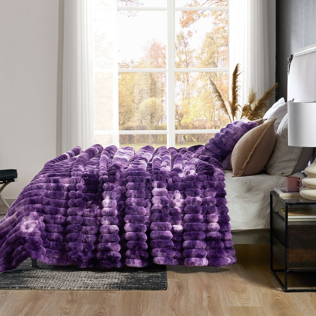 Purple textured blanket draped over a bed in a bedroom with a window in the background. #color_Tie-dye Purple