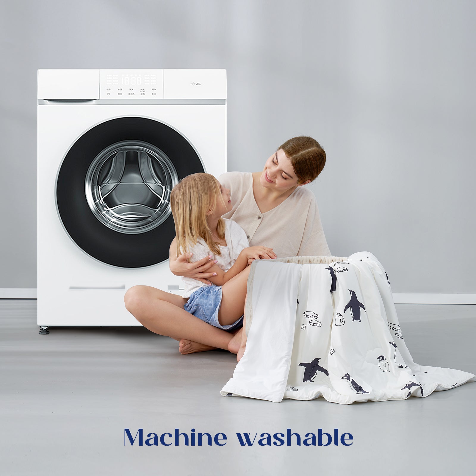 Woman and child with a machine washable comforter in front of a washing machine.#color_Antarctic Penguin