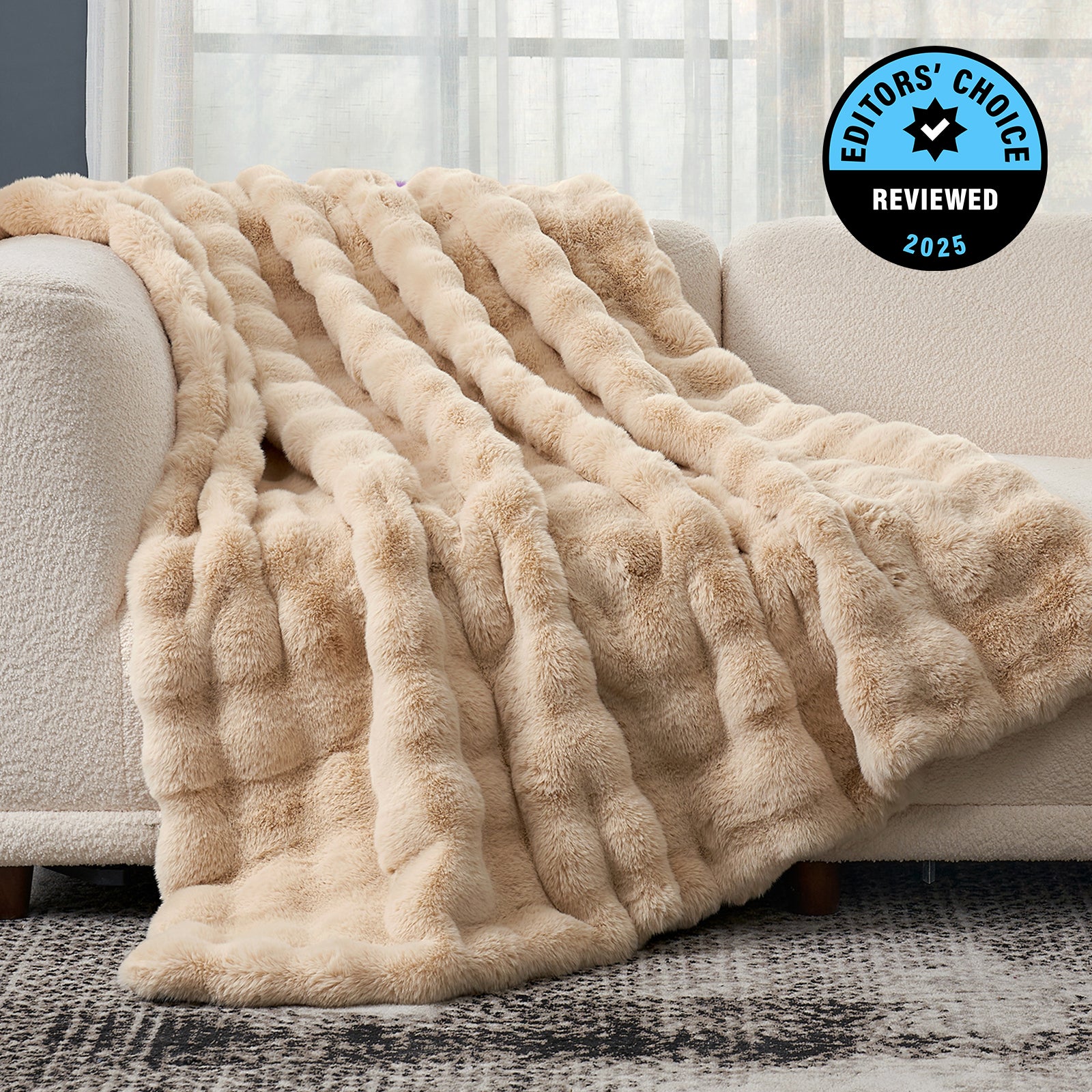 Beige fluffy blanket draped over a couch with 'Editors' Choice' badge in the corner. #Color_Beige