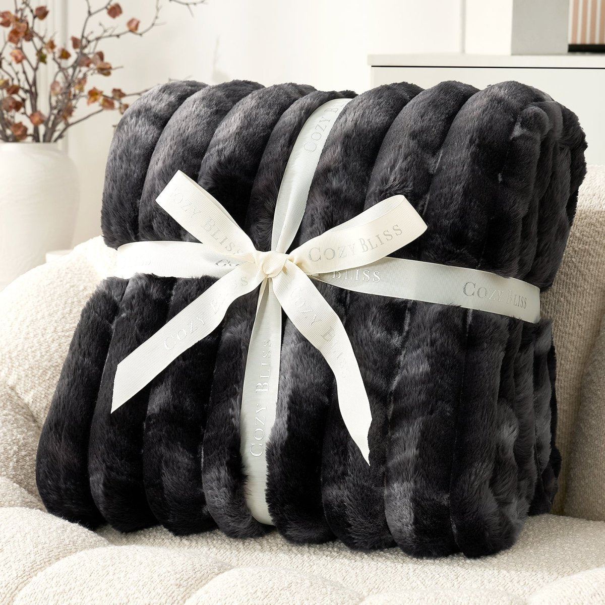 Black blanket with a white ribbon on a beige couch. #color_Tie-dye Black