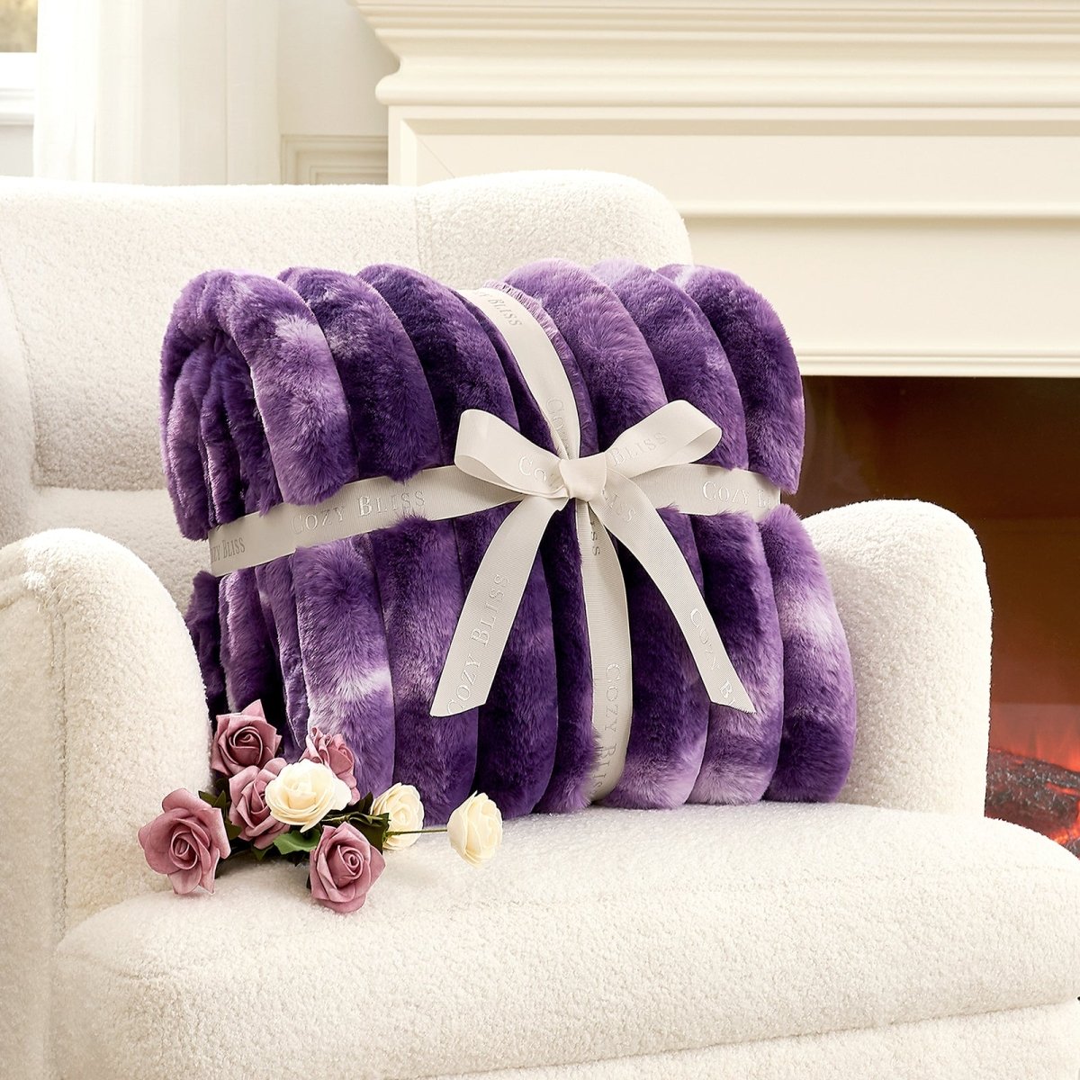 Purple blanket with a white ribbon on a white armchair next to pink flowers. #color_Tie-dye Purple