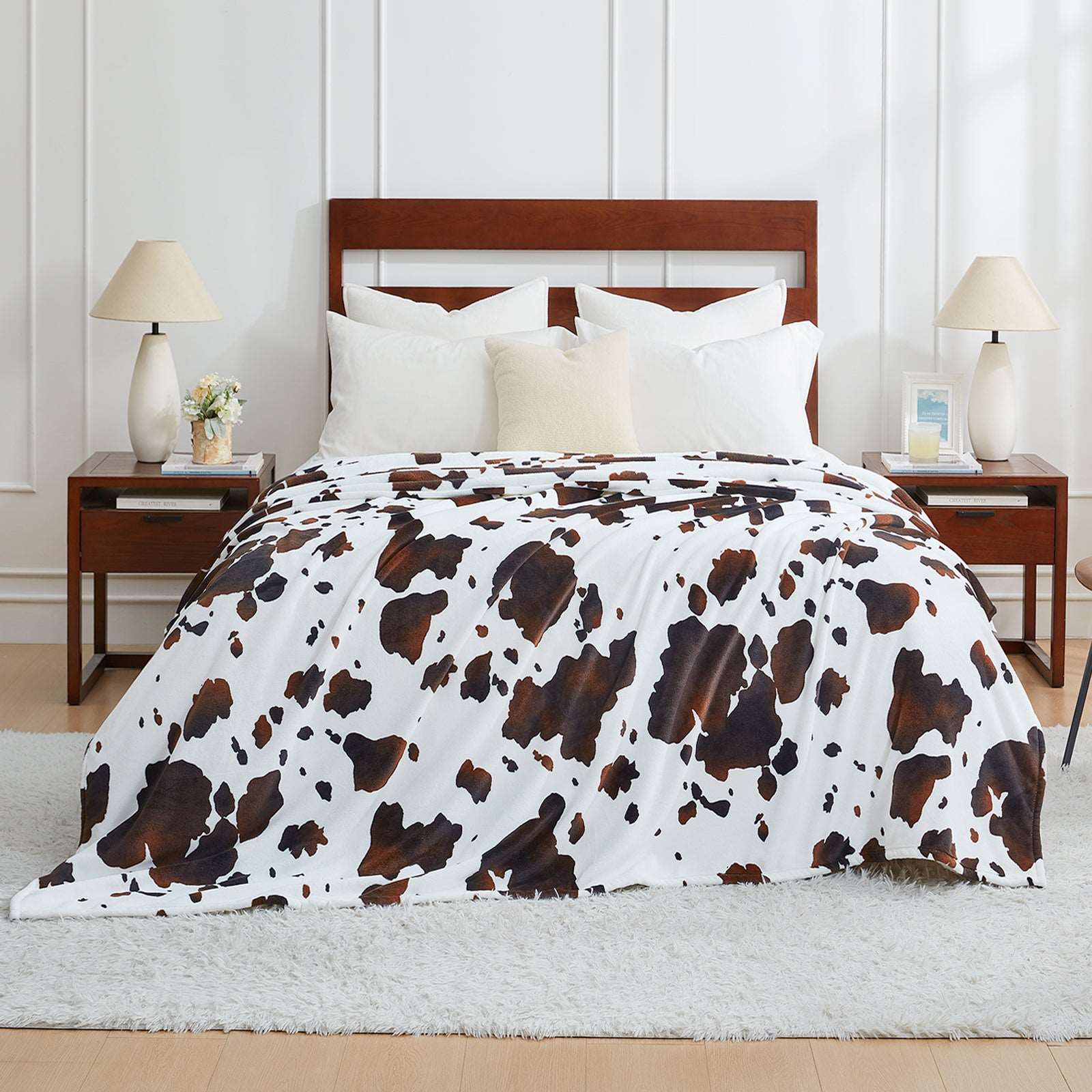 Cozy Cow Print Blanket on bed. Premium soft, breathable, and easy-care blanket. #color_Black Brown
