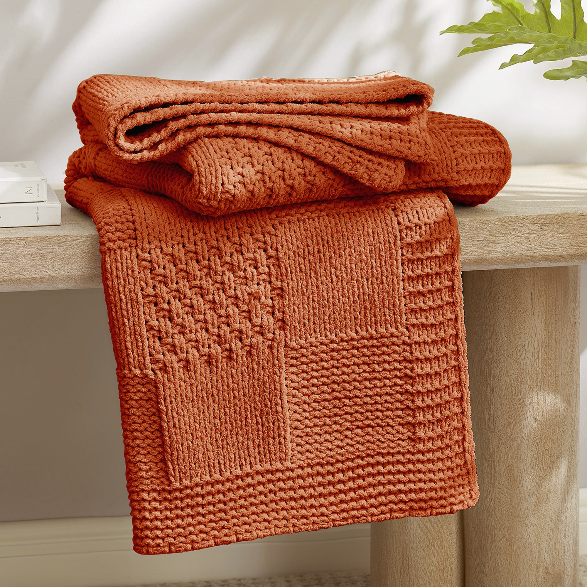 Checkered Chenille Knit Throw Blanket in Burnt Orange neatly folded on a table, showcasing detailed knit texture and soft chenille fabric. #color_Burnt Orange
