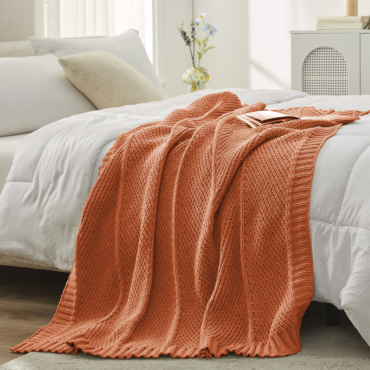 Chevron Chenille Knit Throw Blanket in Orange styled on a bed, adding a vibrant and warm touch to decor. #color_Orange