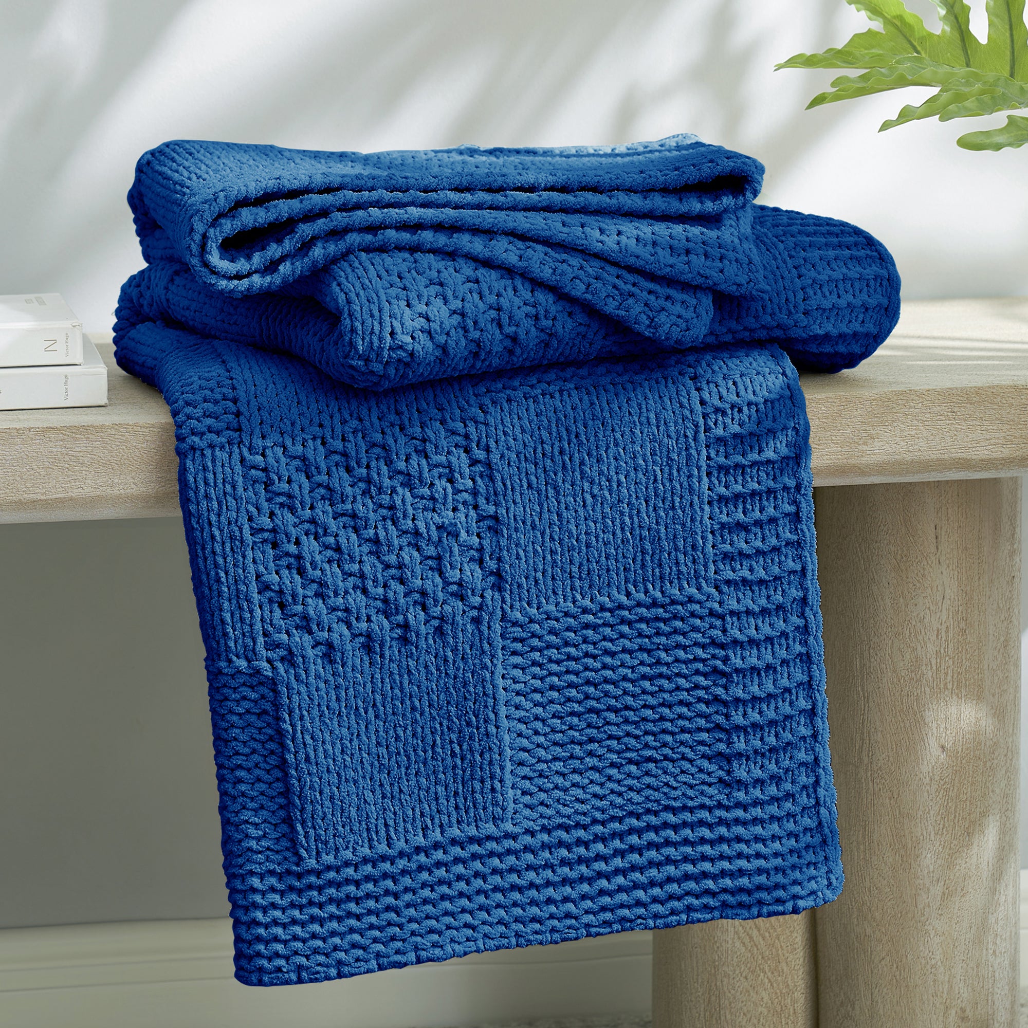 Checkered Chenille Knit Throw Blanket in Blue neatly folded on a table, showcasing detailed knit texture and soft chenille fabric. #color_Dark Blue