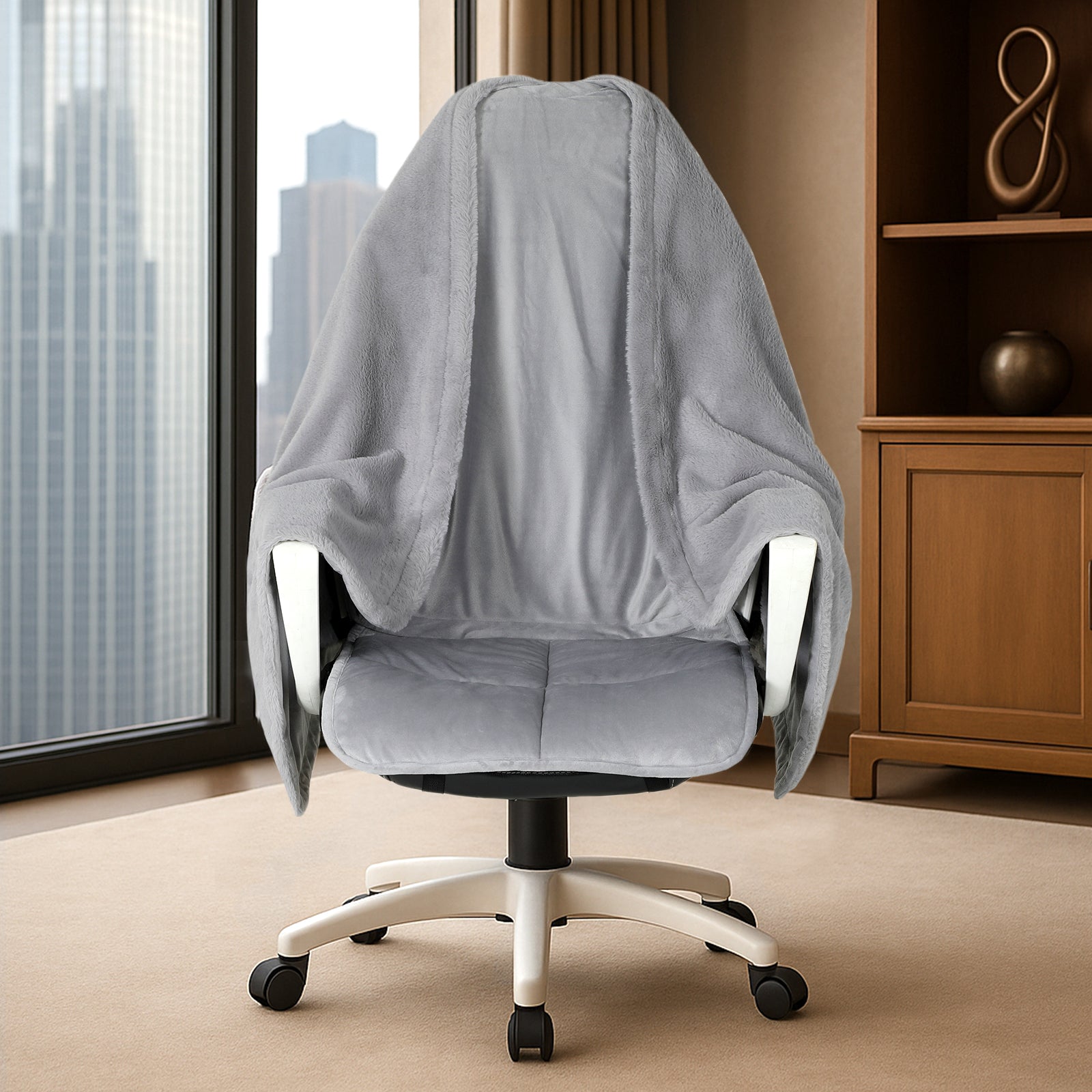 Gray office chair with a blanket draped over it in a room with a large window and wooden cabinet. #color_Grey