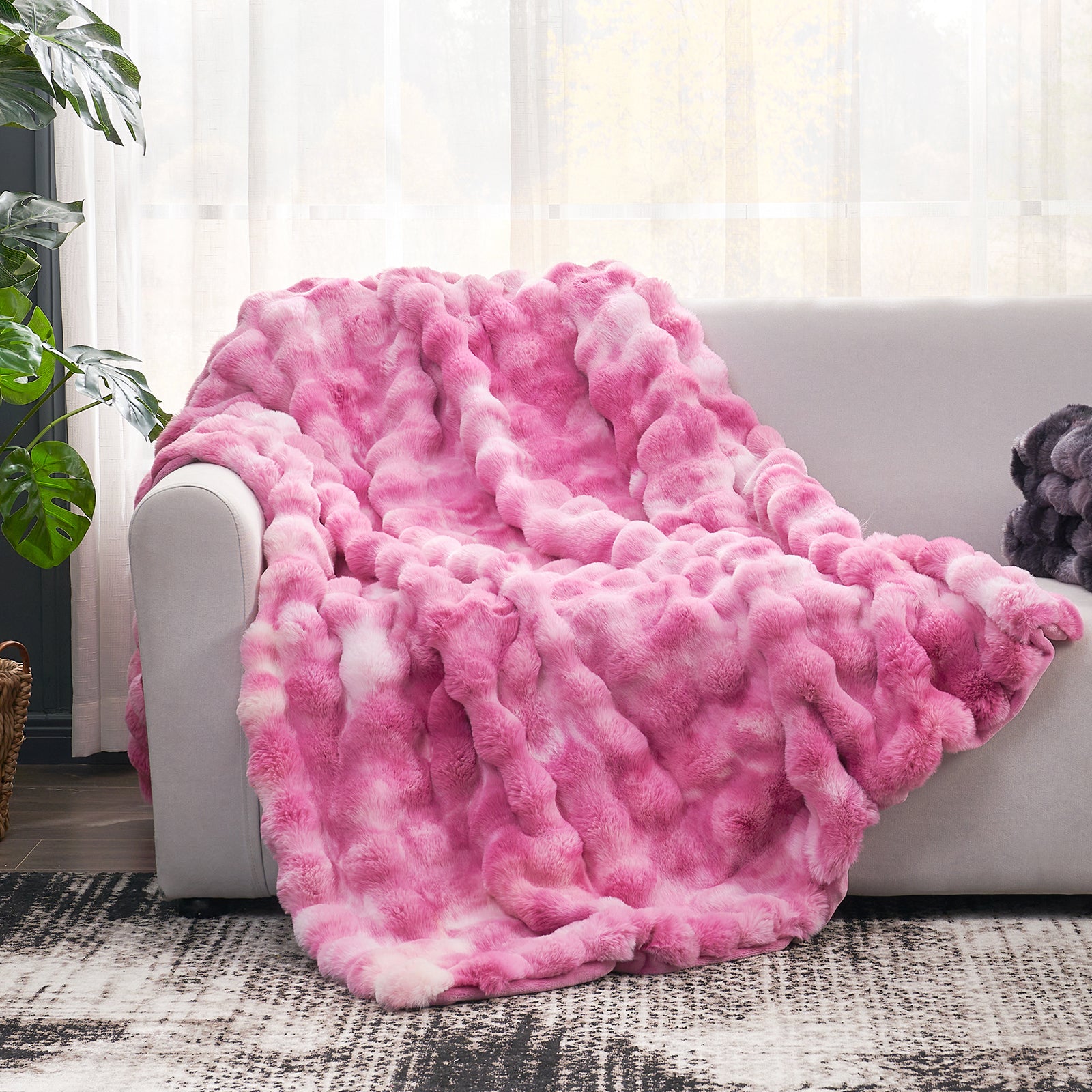 Cozy Bliss pink tie-dye faux fur throw blanket draped over a sofa, a cozy and soft blanket #color_Tie-dye Pink