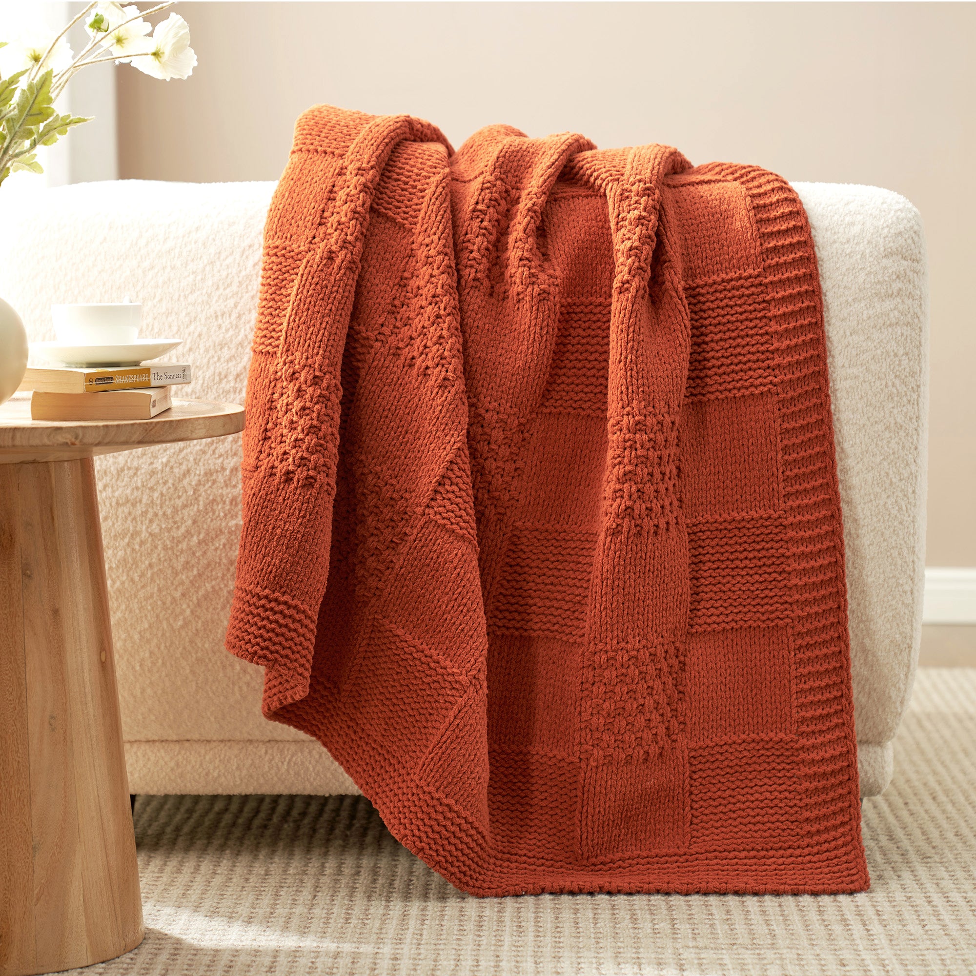 Checkered Chenille Knit Throw Blanket in Burnt Orange draped over a sofa armrest, highlighting soft chenille texture and detailed checkered knit design. #color_Burnt Orange