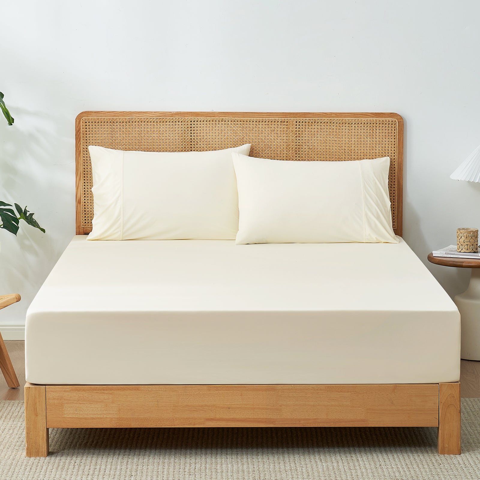 Cream-colored cooling fitted sheet set with pillowcases on a bed with wooden headboard. #Color_Cream White