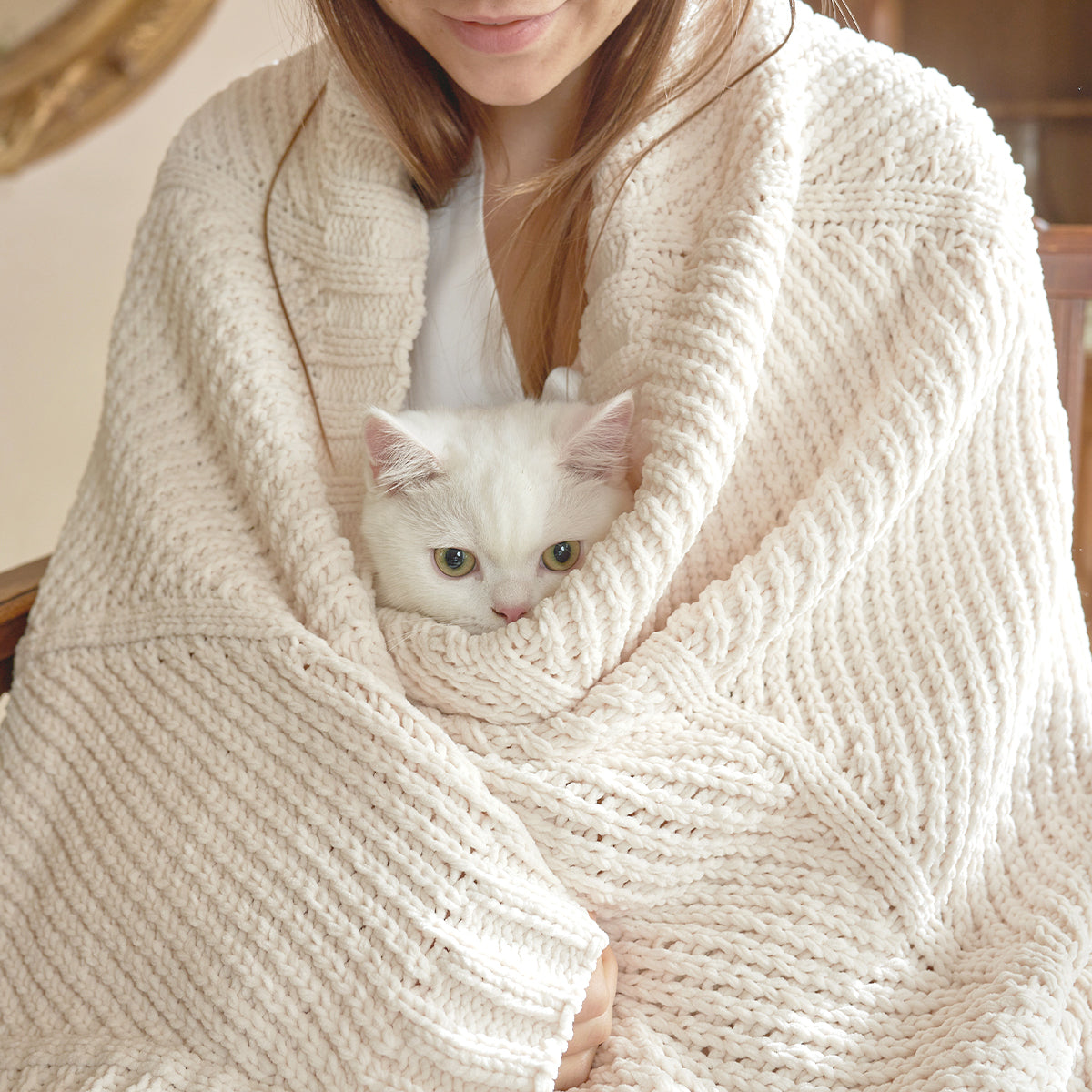 Person wrapped in a cozy ivory blanket with a white cat peeking out.#color_Ivory