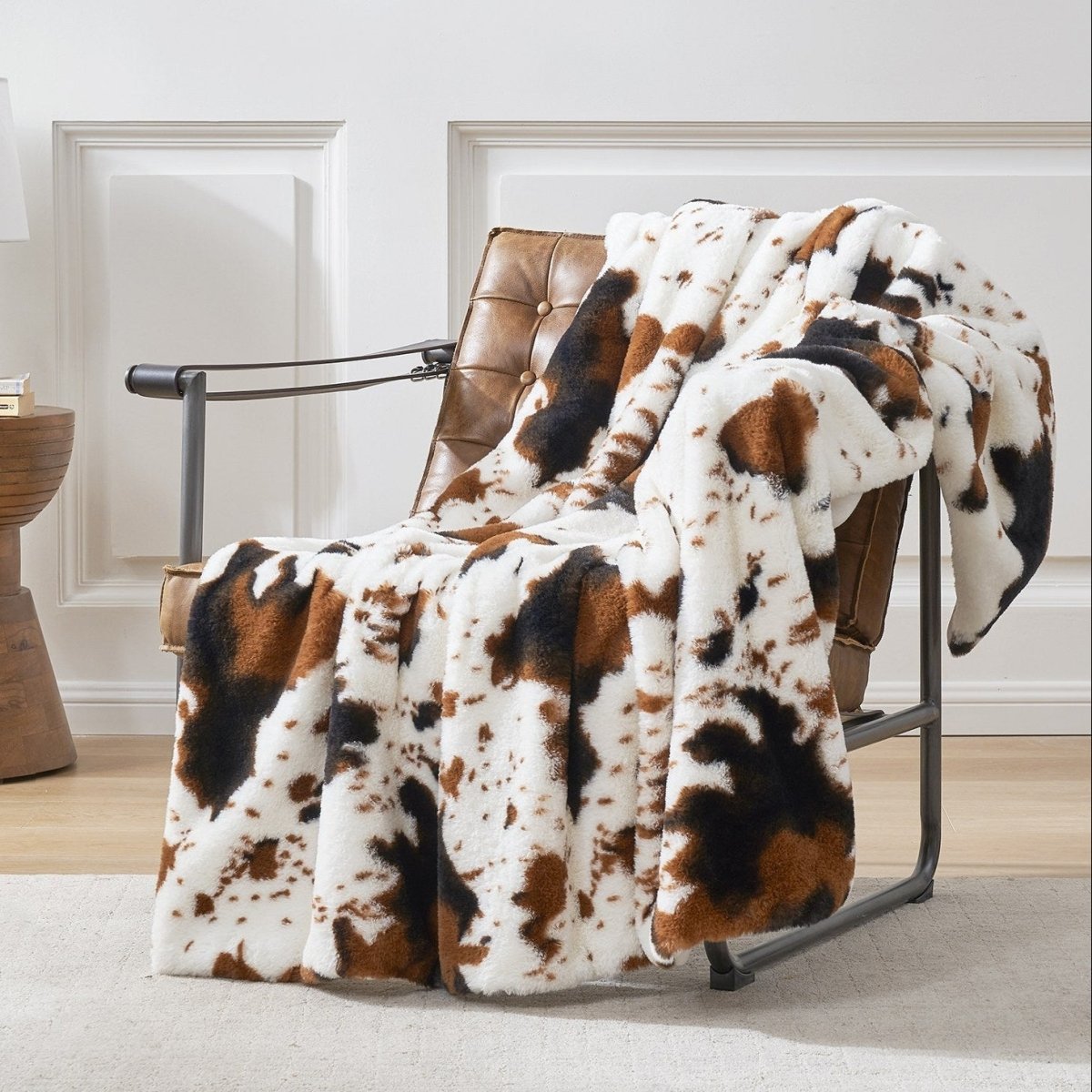 Cow print faux fur blanket draped over leather chair; cozy and stylish home decor #color_Black/Brown Cow