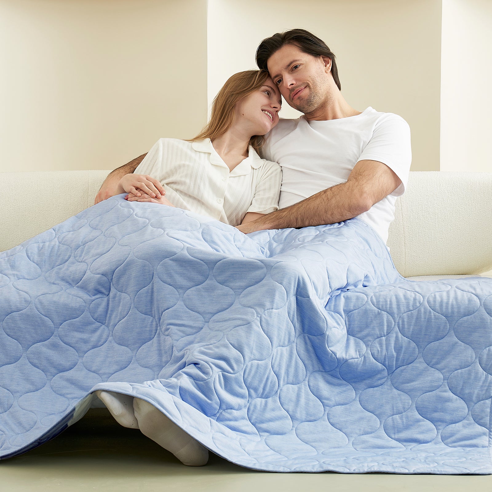 Couple relaxing under a light blue cooling blanket on a sofa, cozy bedding #color_Cool Blue