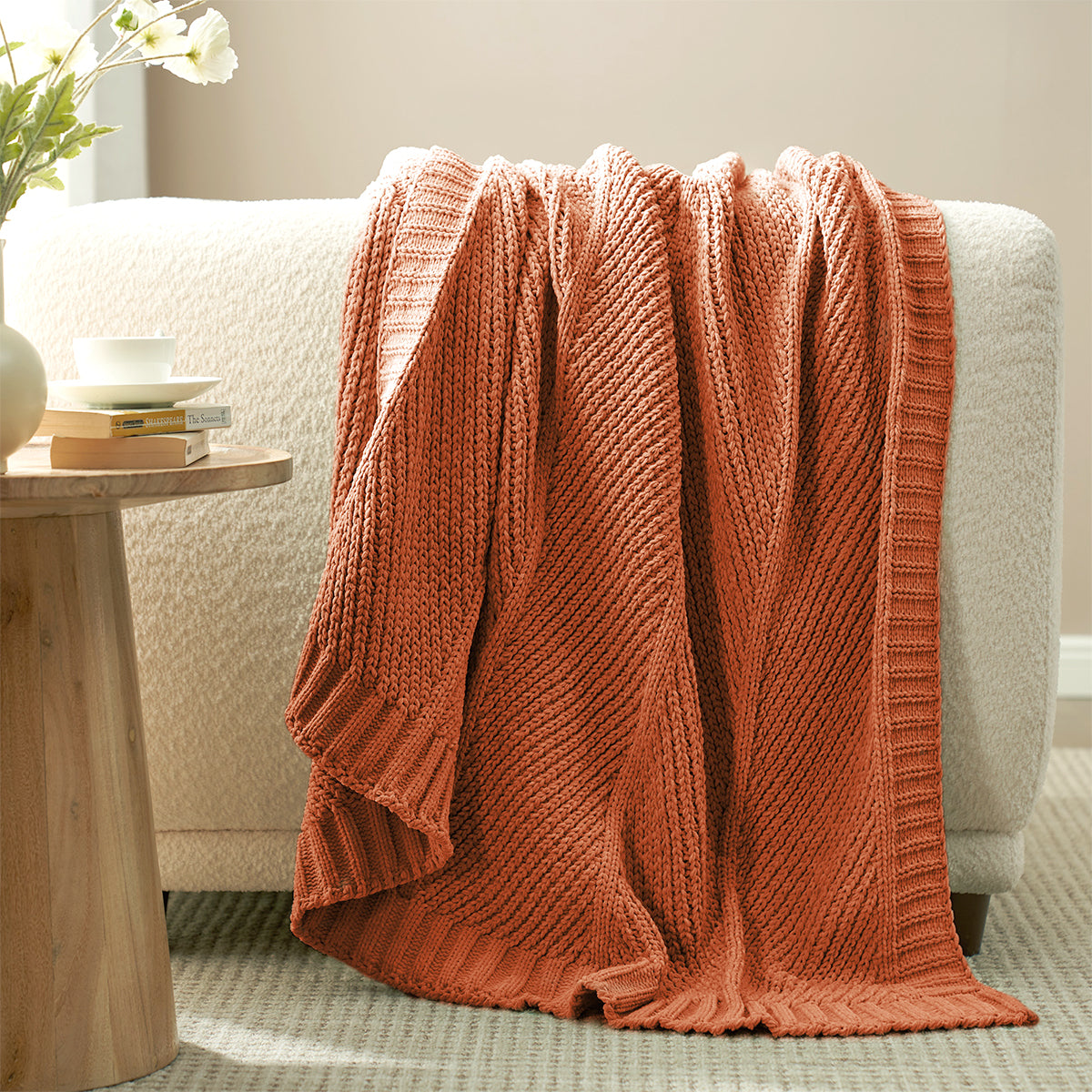 Chevron Chenille Knit Throw Blanket in Orange draped over a sofa, showcasing its soft chenille texture and warm textured design. #color_Orange