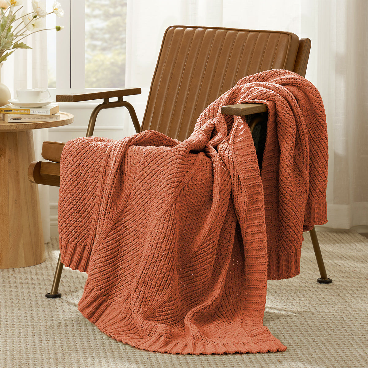 Ivory knitted blanket draped over a orange armchair in a room with a table and window. #color_Orange