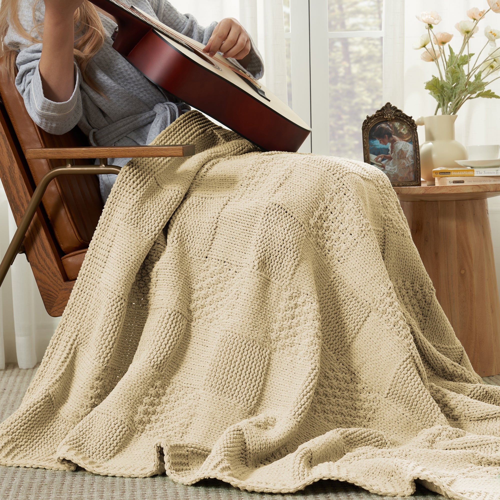 Person playing guitar while using Checkered Chenille Knit Throw Blanket in Beige, enjoying cozy comfort in a warm living room setting. #color_Beige