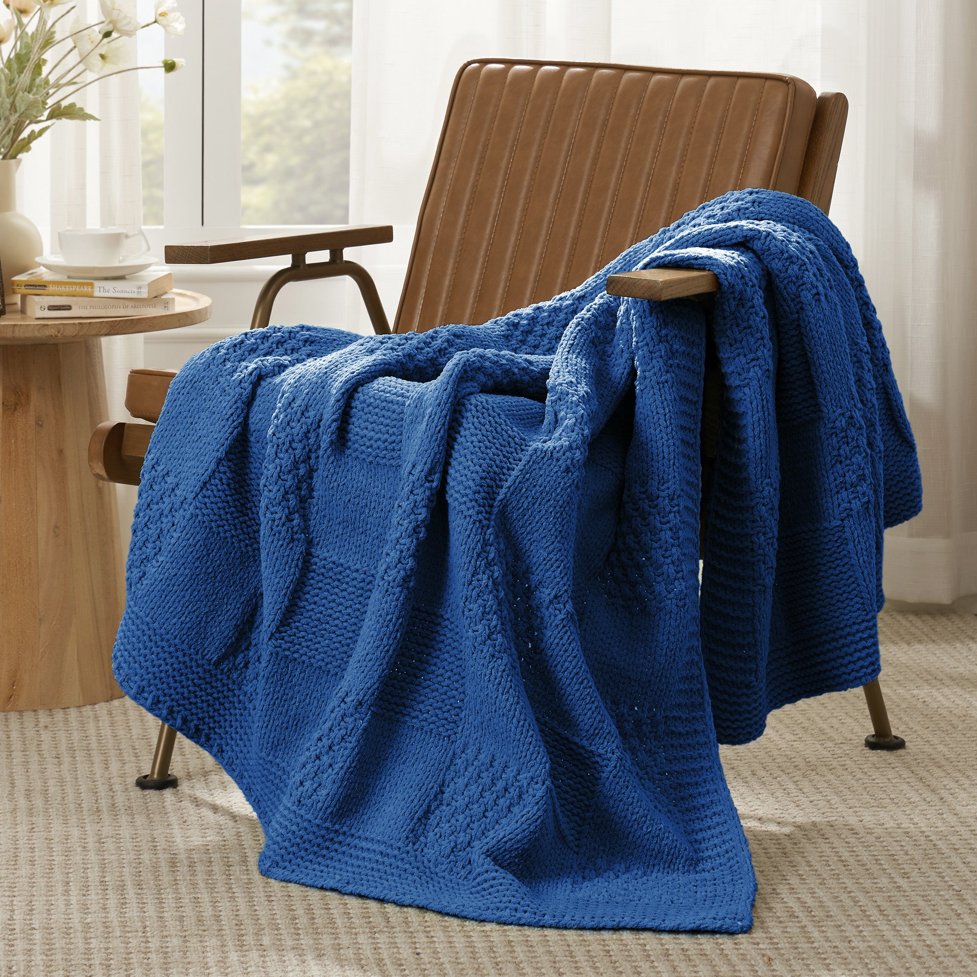 Checkered Chenille Knit Throw Blanket in Blue draped over a lounge chair, showcasing soft chenille knit texture and cozy checkered design. #color_Dark Blue