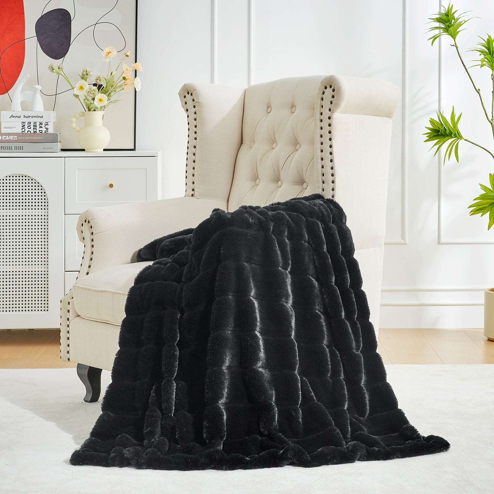Black faux fur blanket draped over a cream armchair. CozyBliss throw for living room or bedroom. #color_Black