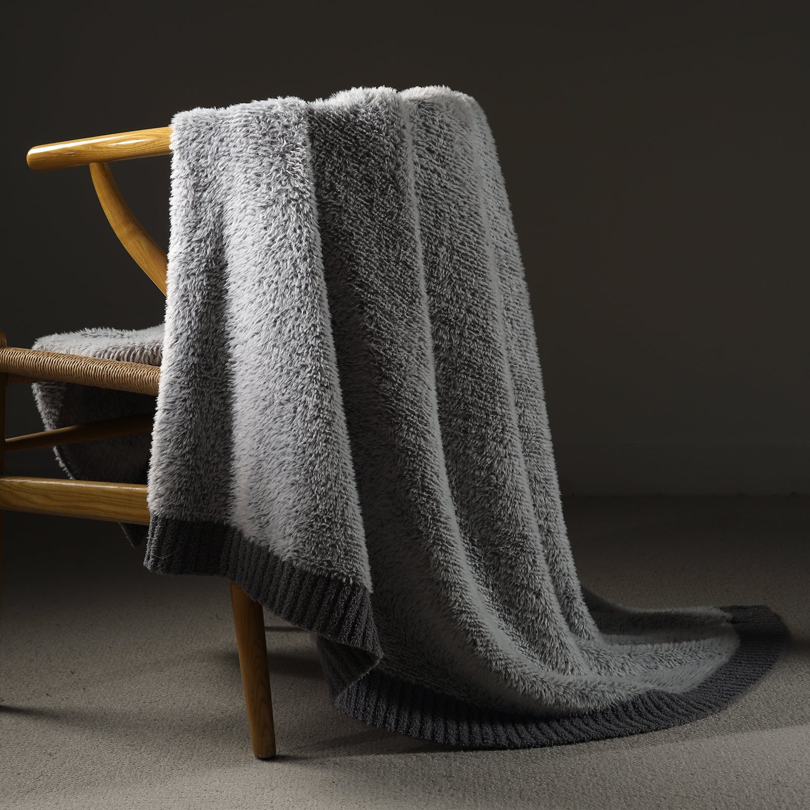 Faux Mink Feather Knit Throw Blanket in Grey draped over a chair, showcasing soft faux mink texture and elegant knit design. #color_Grey