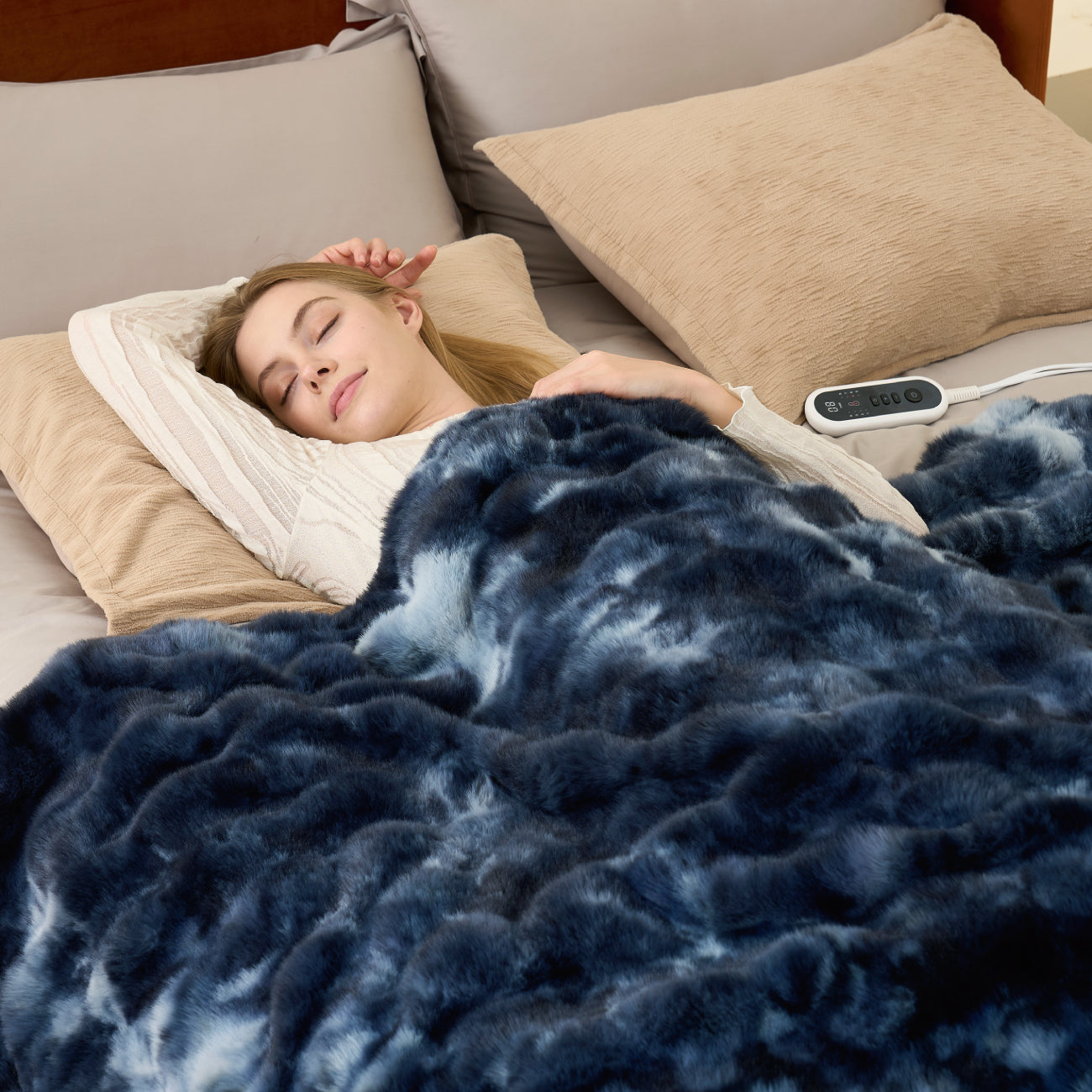 Woman sleeping under a blue weighted blanket with a remote control on a bed.  #color_Tie-dye Blue