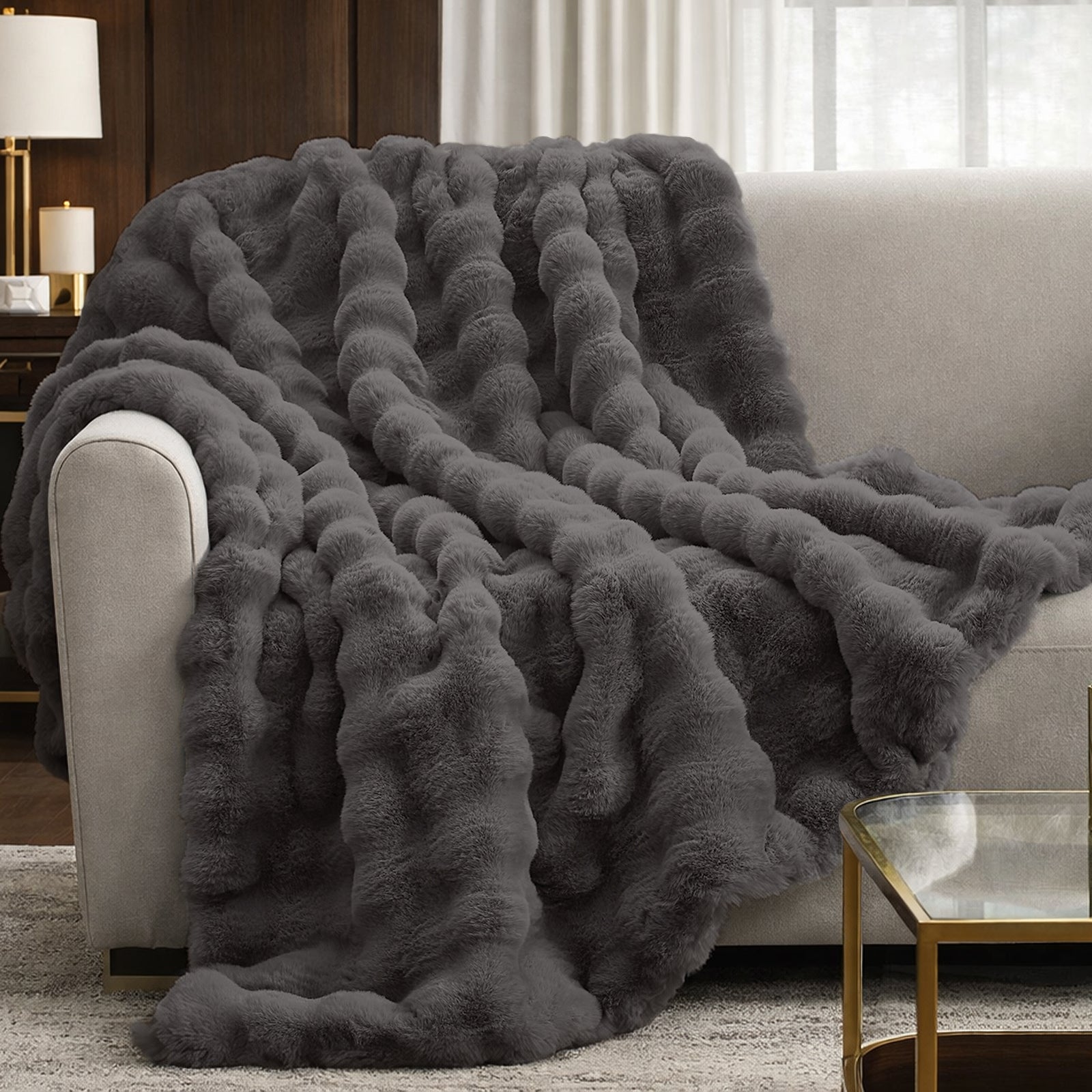 Cozy Bliss Bubble Faux Fur Throw Blanket draped over a couch #color_Charcoal Grey