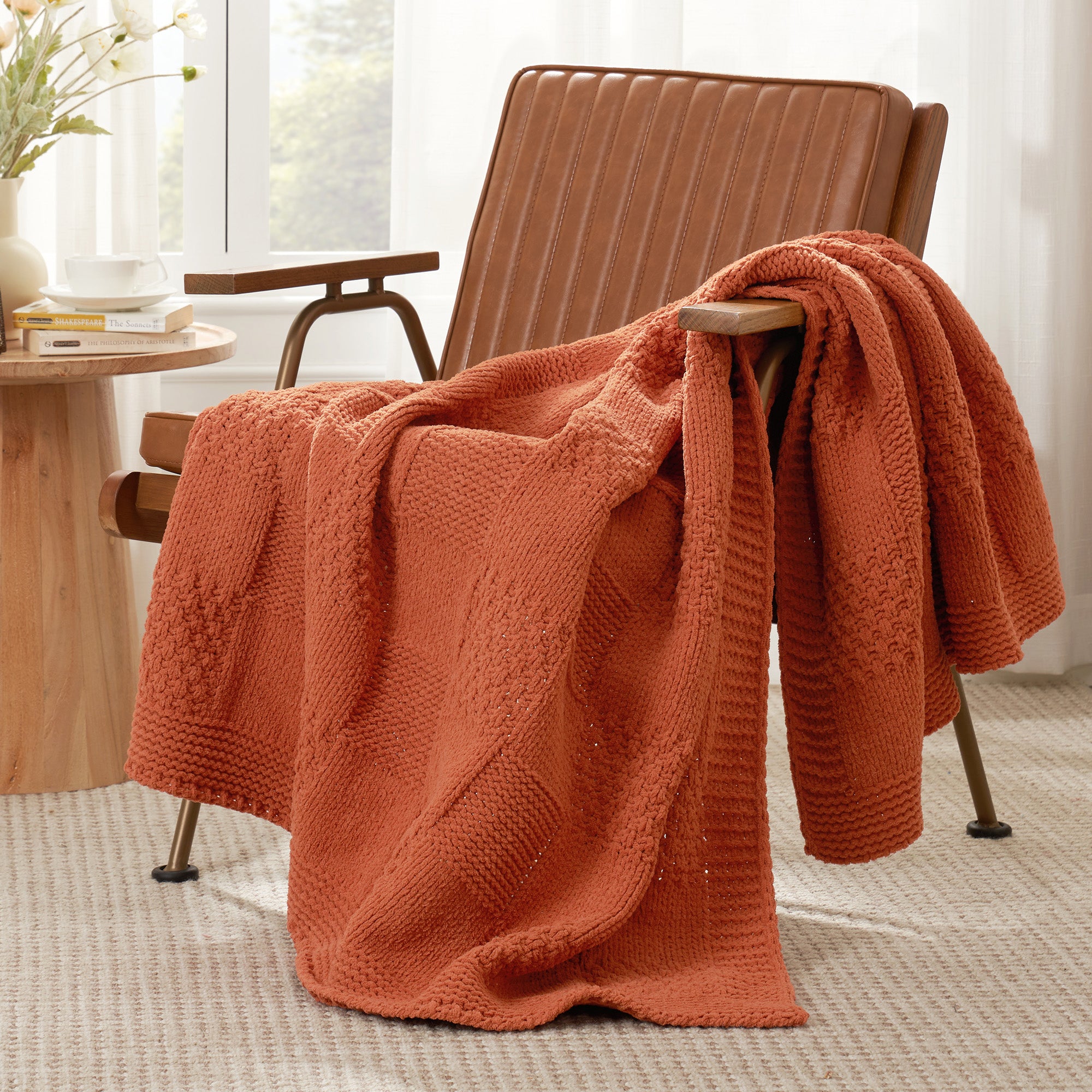 Checkered Chenille Knit Throw Blanket in Burnt Orange draped over a lounge chair, showcasing soft chenille knit texture and cozy checkered design. #color_Burnt Orange
