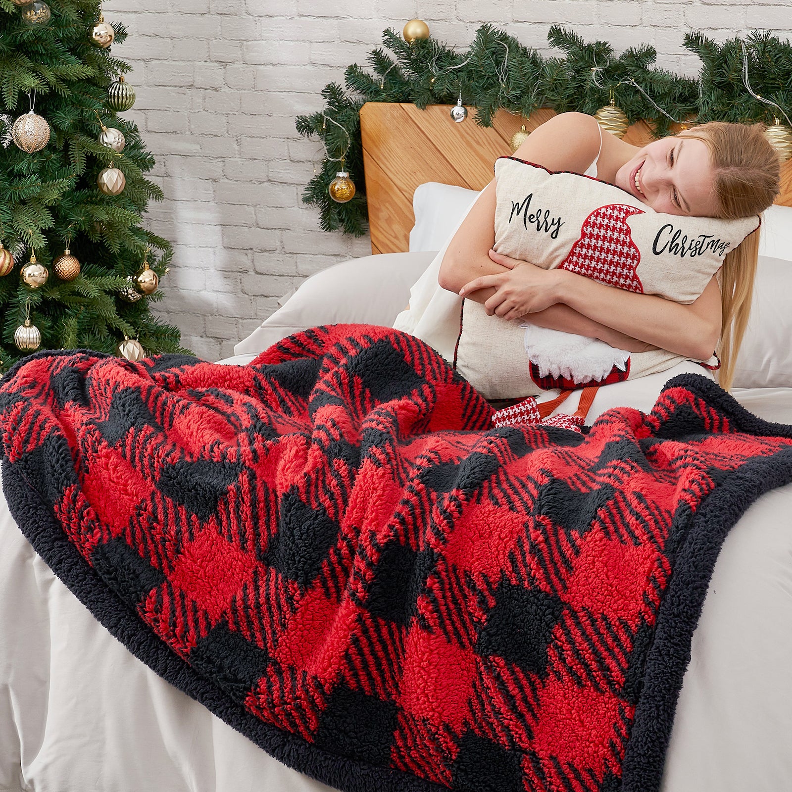 Person lying on a couch with a red and black checkered blanket, holding a pillow with Christmas text, in a festive room. #Color_Red/Black Buffalo Check