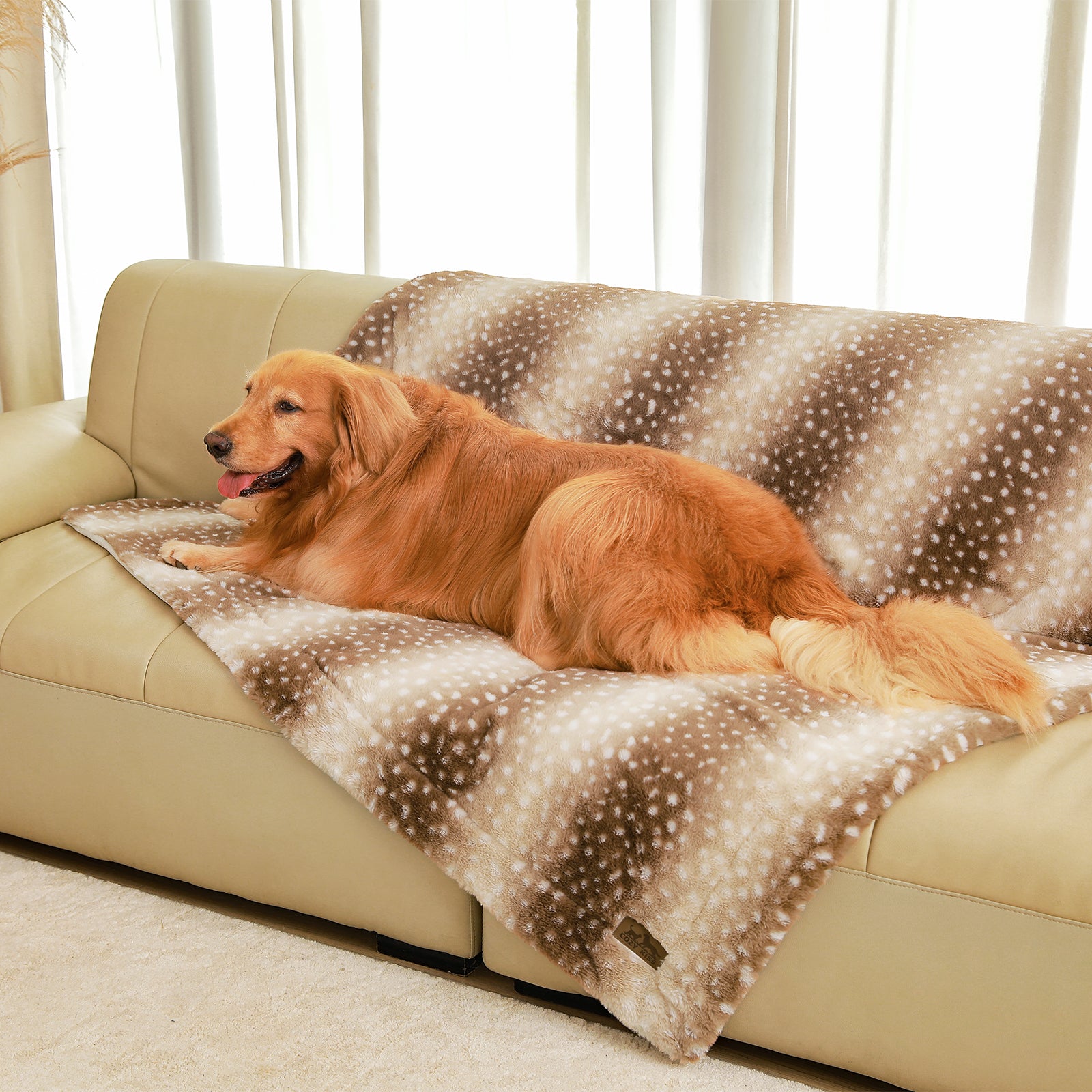 Dog sitting on a cozy bliss leakproof faux fur pet blanket on a sofa, smiling. #color_Brown Sherpa Deer