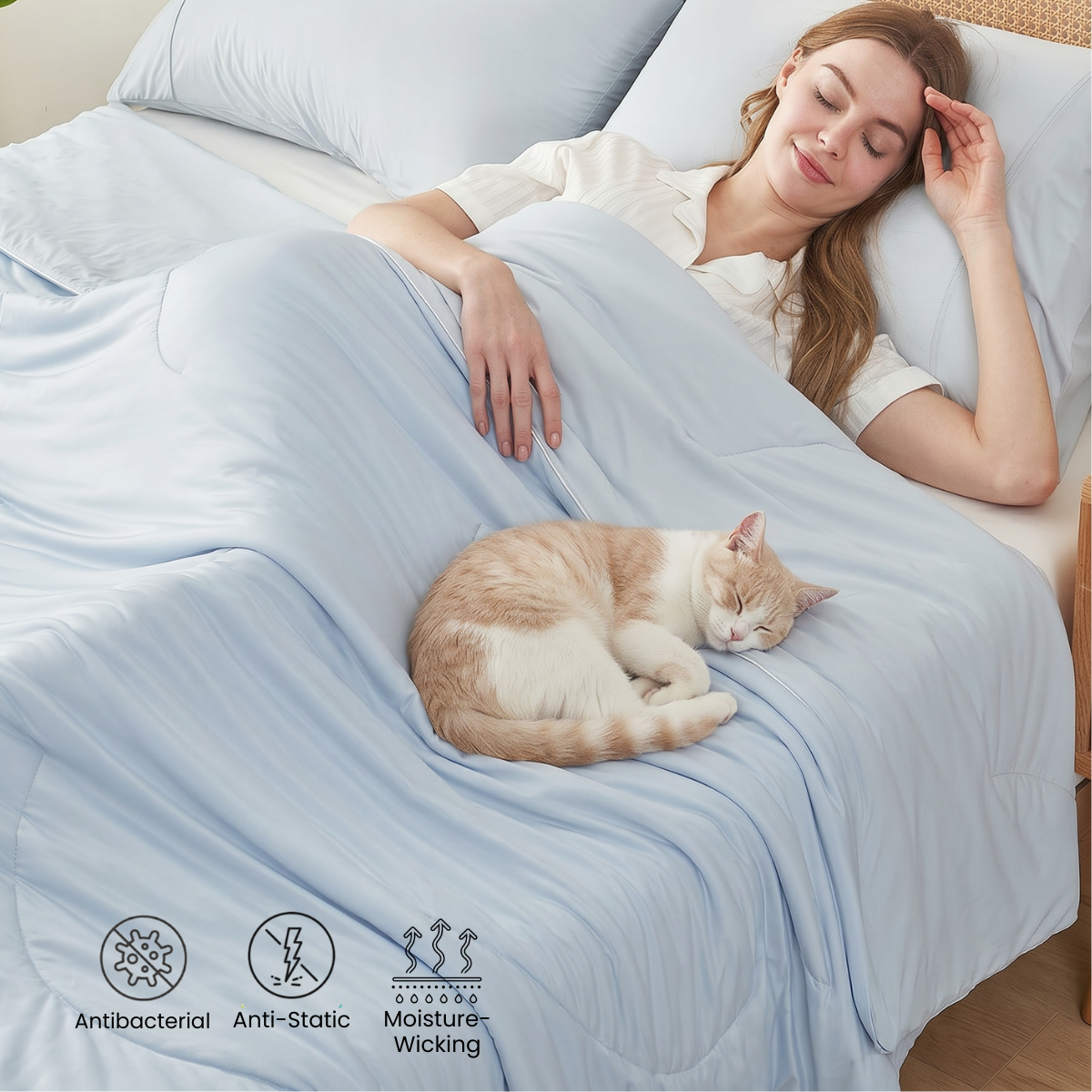 Woman sleeping with a cat on a bed covered with a light blue comforter, featuring antibacterial, anti-static, and moisture-wicking properties.#color_Cool Blue