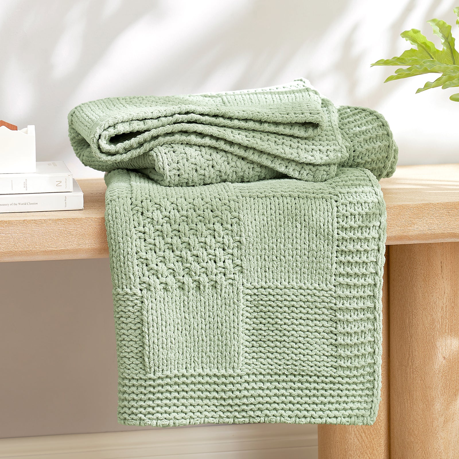 Checkered Chenille Knit Throw Blanket in Sage Green neatly folded on a table, showcasing detailed knit texture and soft chenille fabric. #color_Sage Green