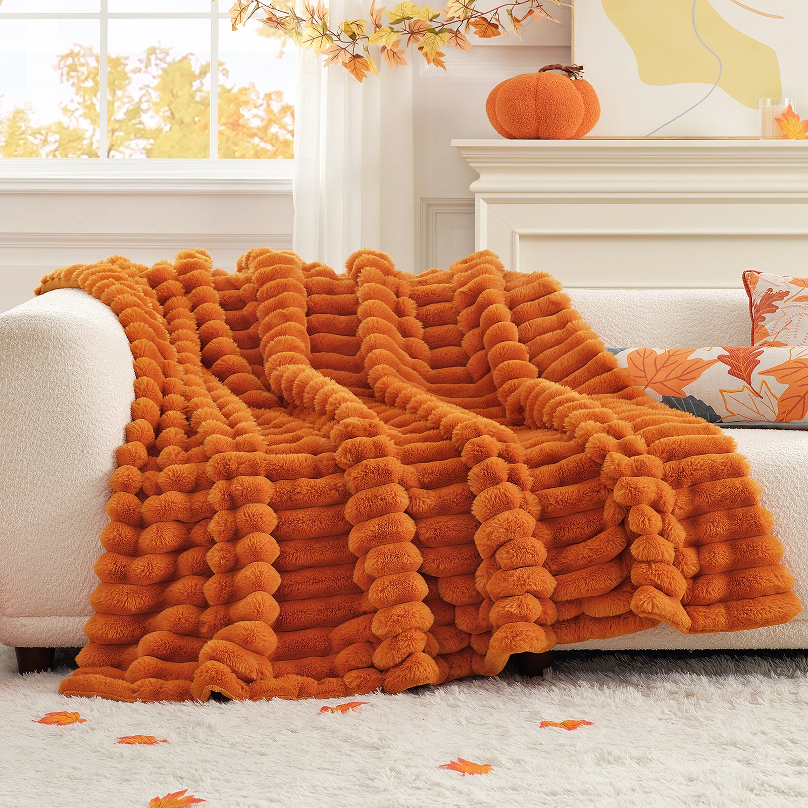 Orange sherpa blanket draped over a sofa in a cozy living room with autumn decorations. #color_Burnt Orange