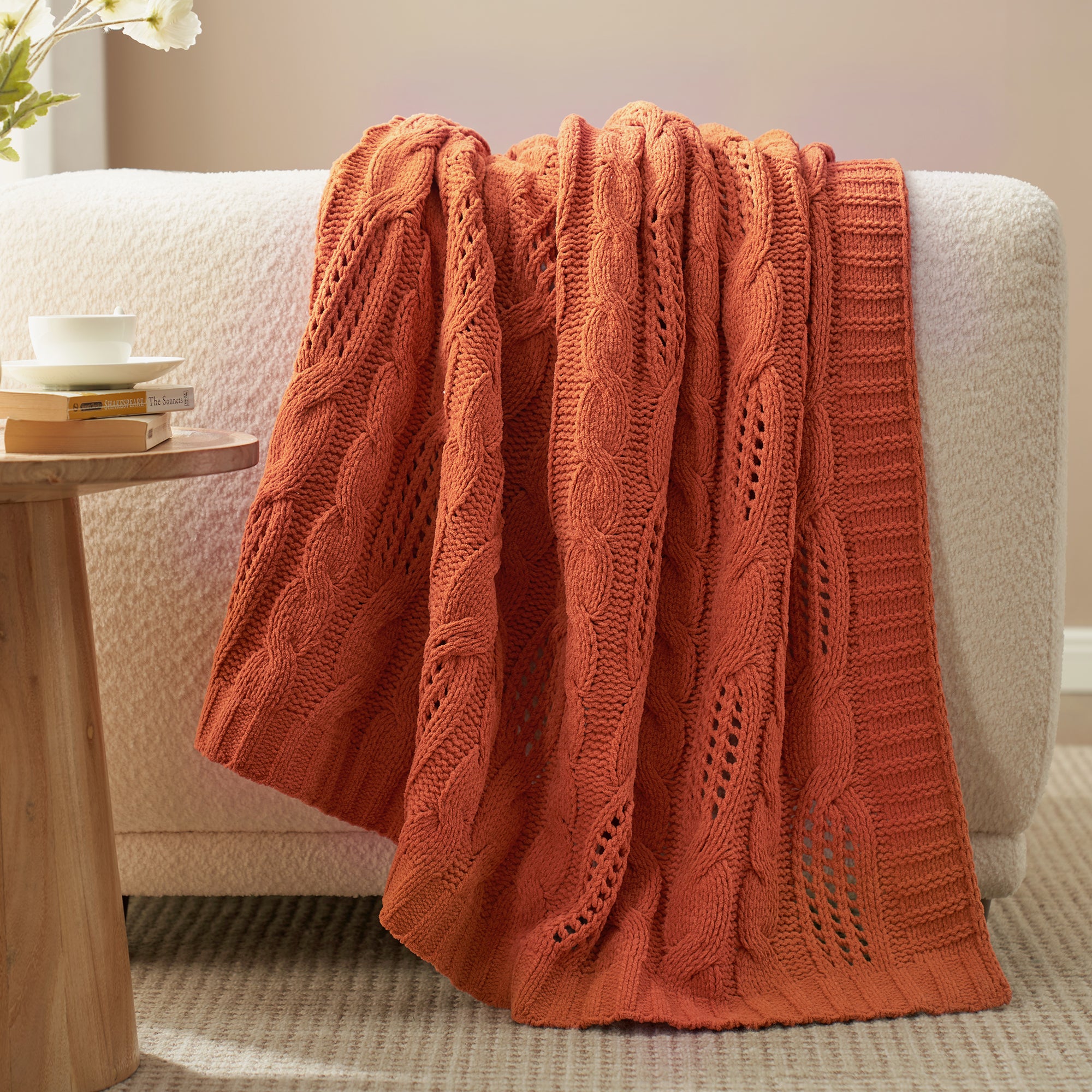 Chenille Cable Knit Throw Blanket in Burnt Orange draped over a sofa, creating a warm atmosphere. #color_Burnt Orange