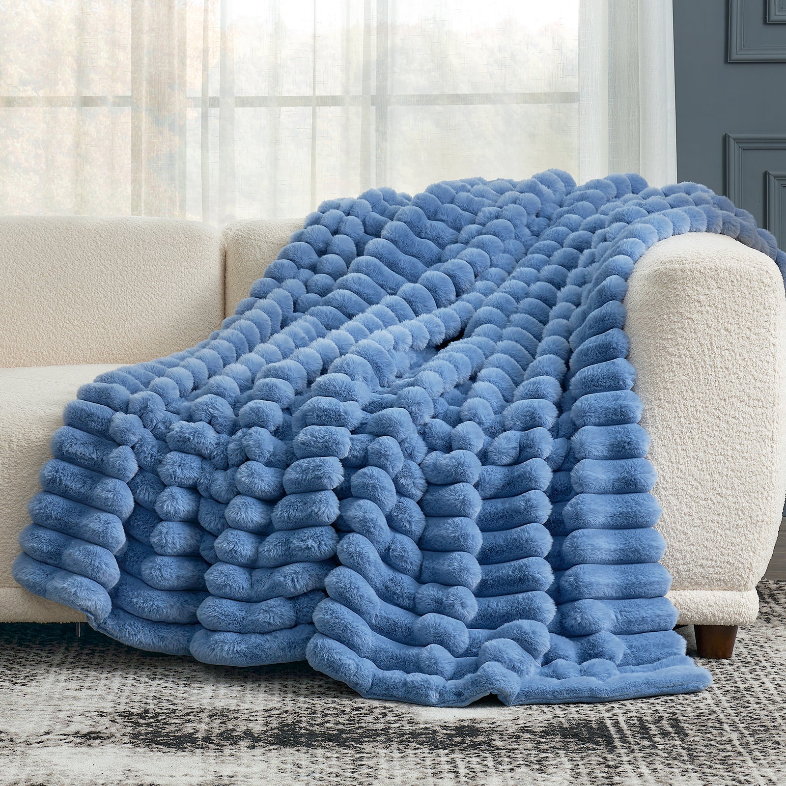 Cozy Bliss blue faux fur blanket on beige sofa. Ultra-soft, cozy blanket for comfortable relaxation. #color_Light Blue