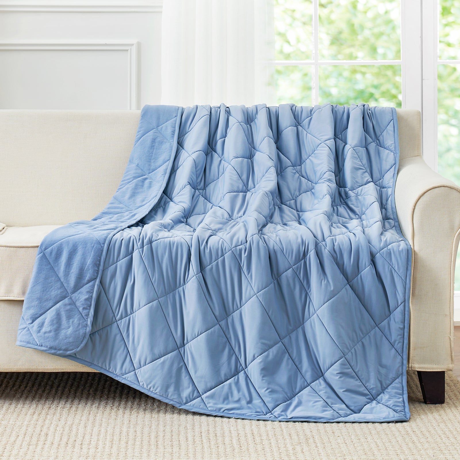 Light blue cooling blanket draped over a couch, a cooling comforter alternative for hot sleepers #Color_Dark Blue