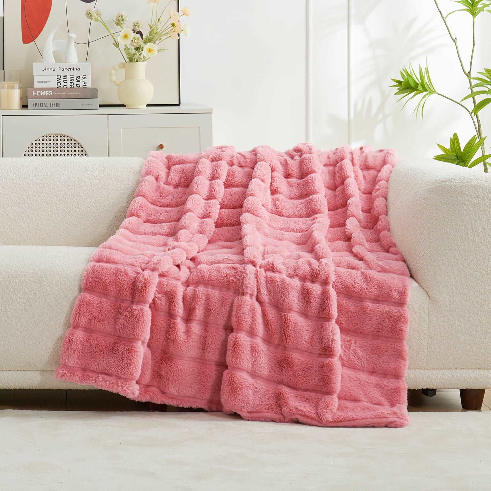 Pink CozyBliss faux fur throw blanket on cream sofa. Soft, fuzzy blanket for a cozy and stylish living room. #color_Pink
