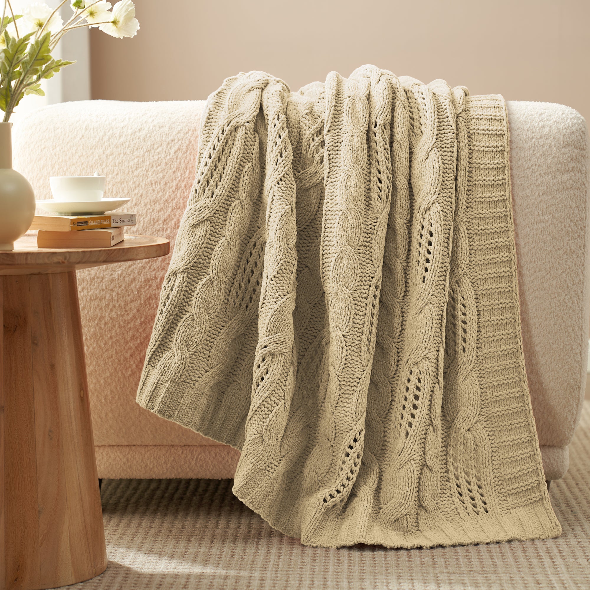 Chenille Cable Knit Throw Blanket in Beige draped over a sofa, creating a warm atmosphere. #color_Beige