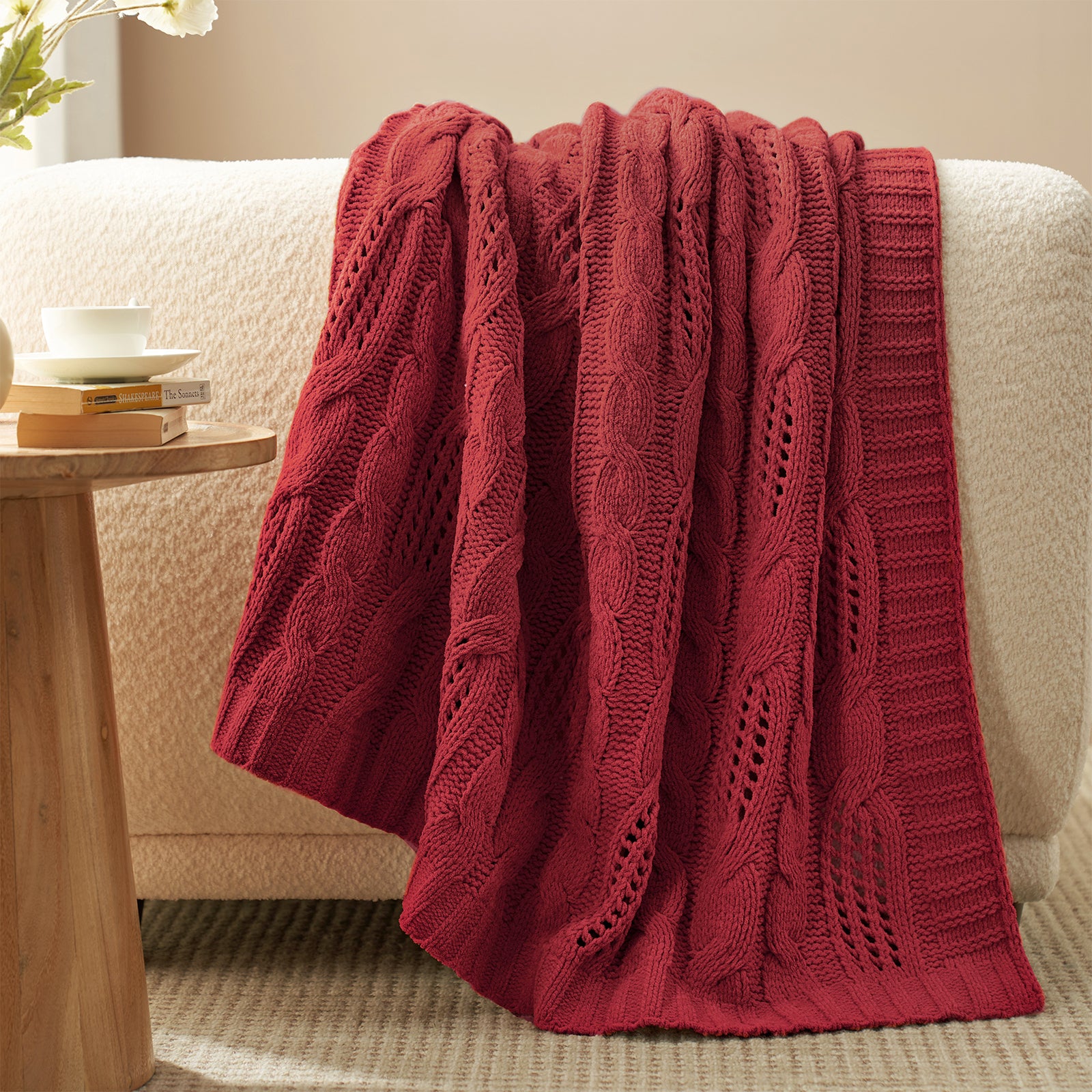 Chenille Cable Knit Throw Blanket in Red draped over a sofa, creating a warm atmosphere. #color_Christmas Red