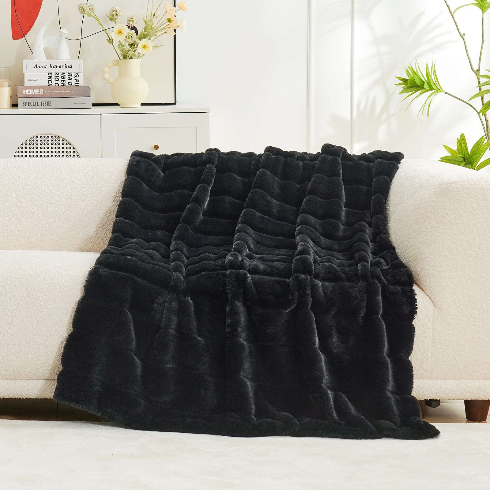CozyBliss Sheared Faux Fur Blanket in Black, draped on a sofa, luxurious and soft #color_Black