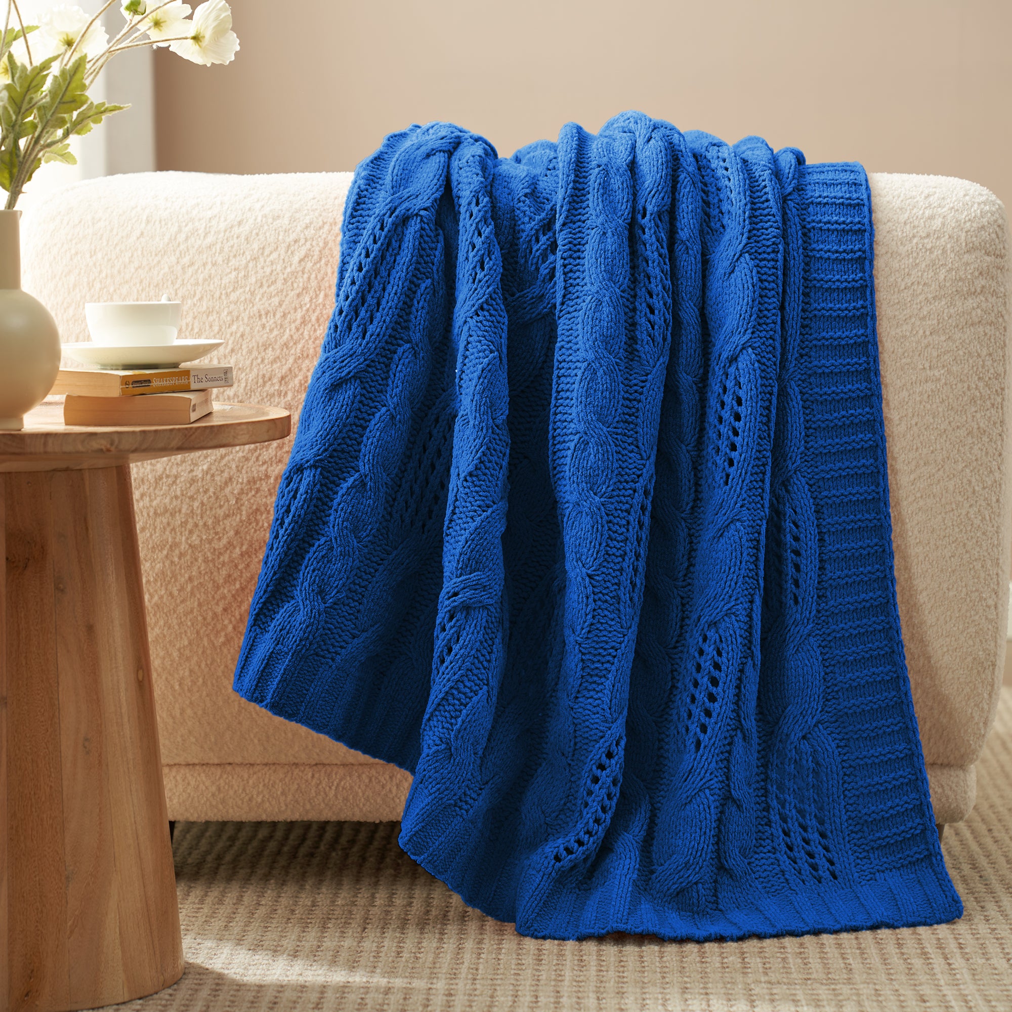 Chenille Cable Knit Throw Blanket in Blue draped over a sofa, creating a warm atmosphere. #color_Blue