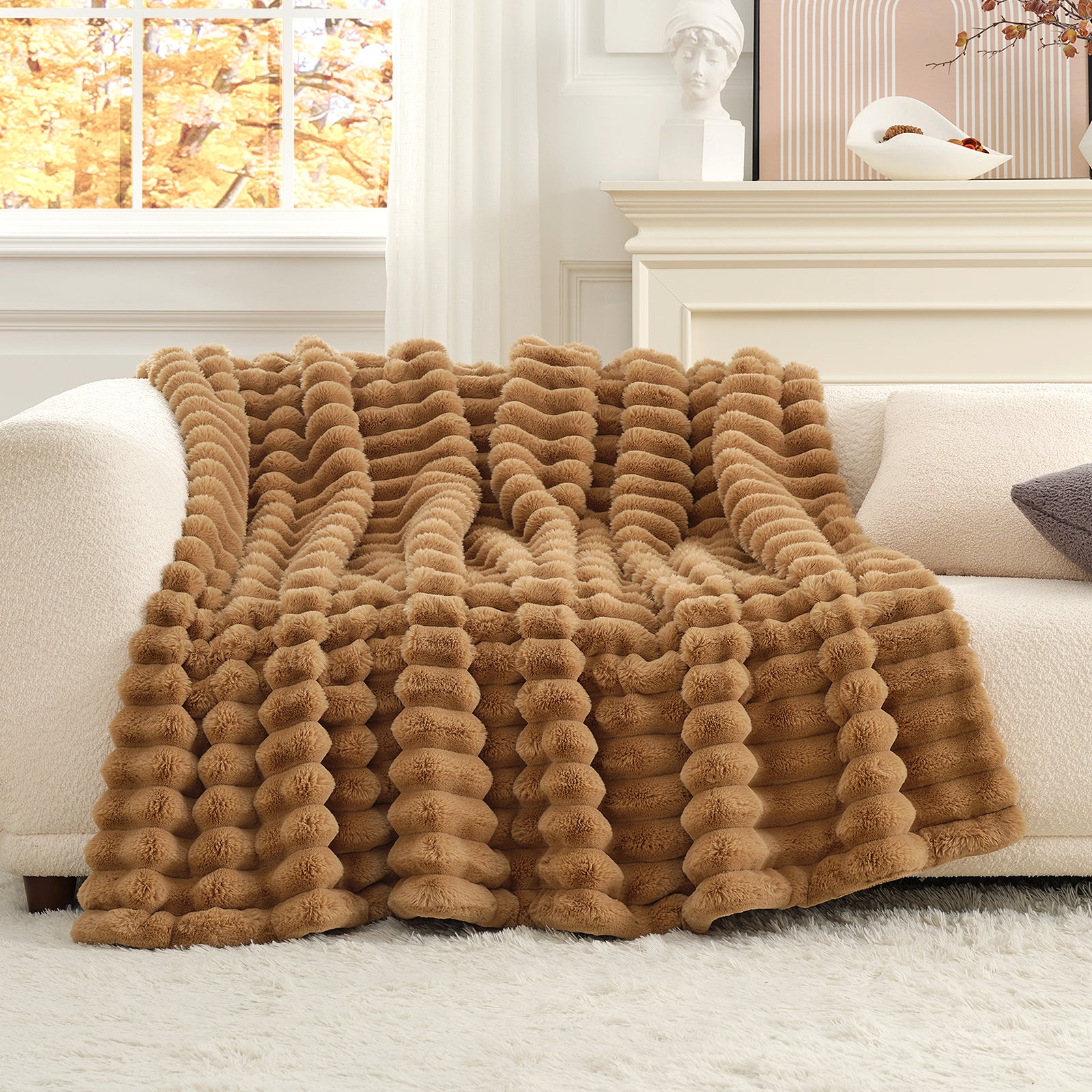 Brown textured blanket on a white sofa in a bright room with a window in the background. #color_Toasty Brown