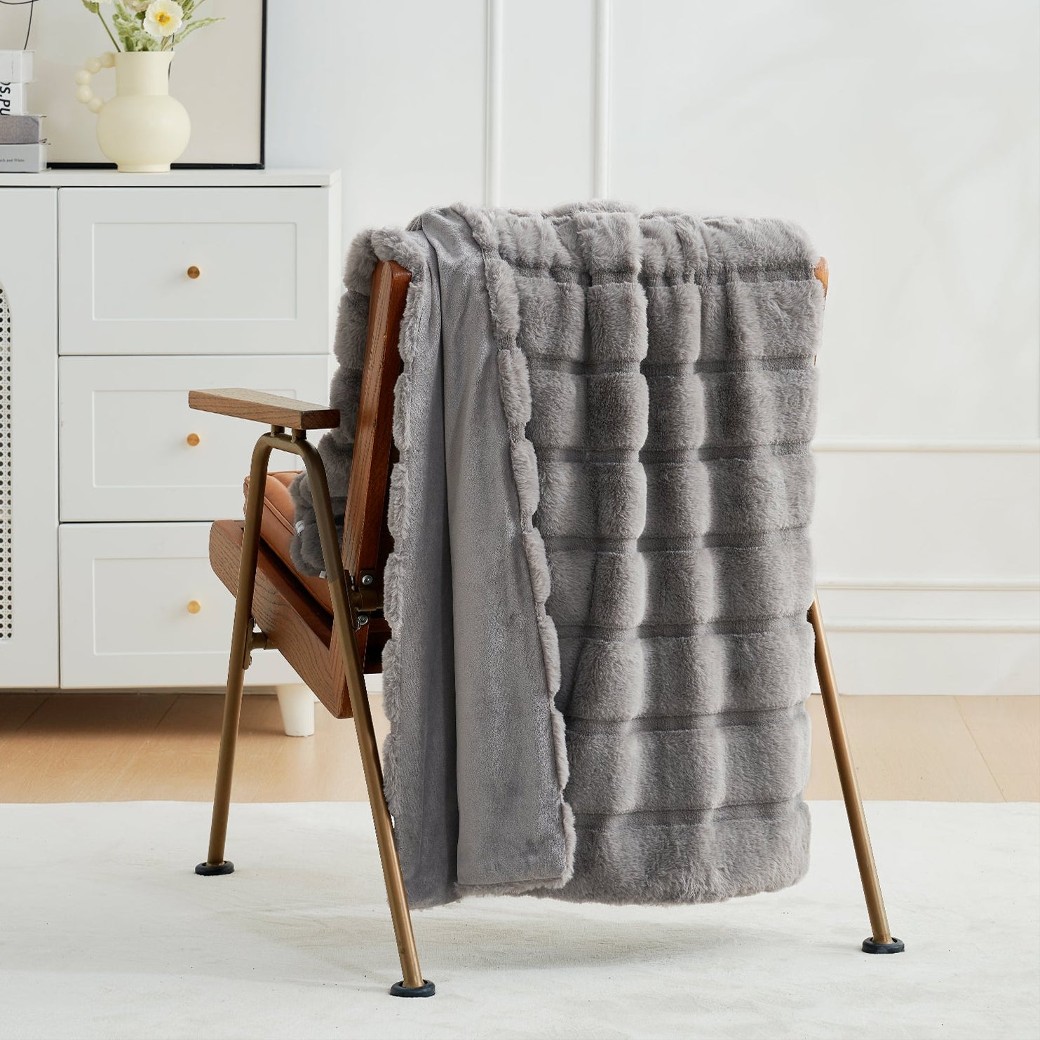 Gray textured blanket draped over a wooden chair in a minimalistic room. #color_Grey