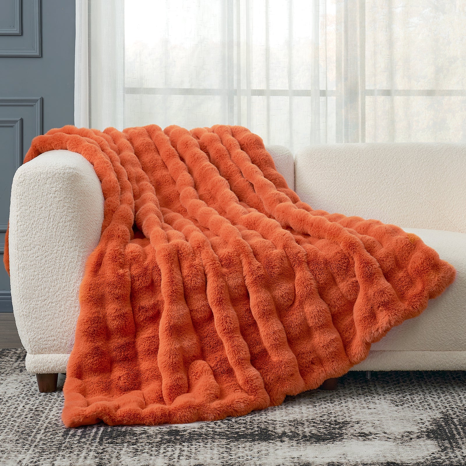 Cozy Bliss orange faux fur throw blanket on white sofa. Soft and cozy blanket for comfort. #color_Burnt Orange