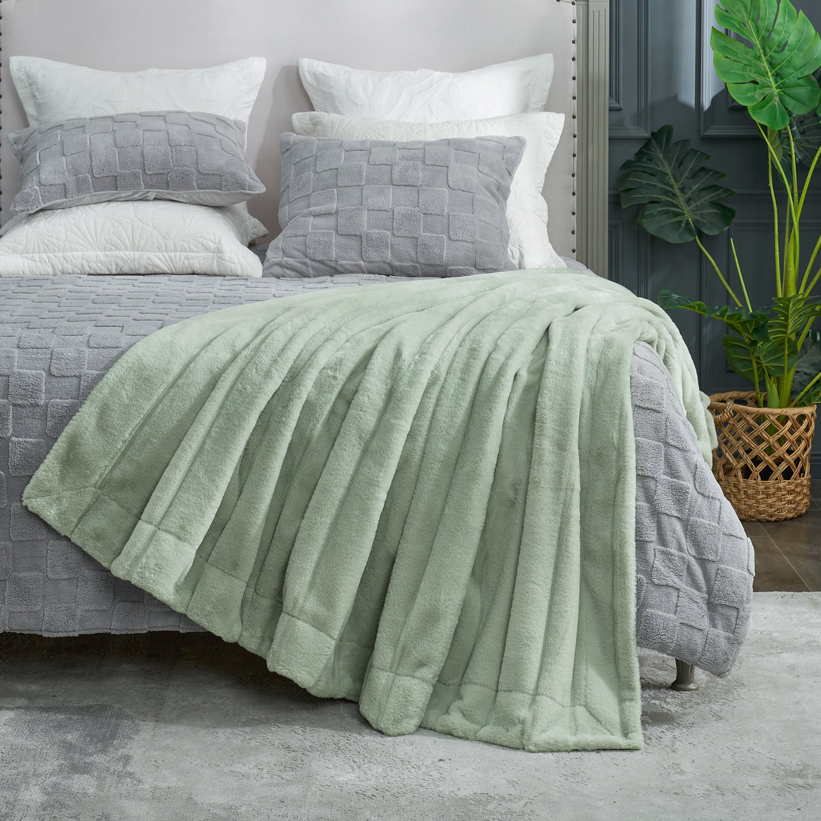 Bed with green blanket and gray pillows in a bedroom setting #color_Sage Green