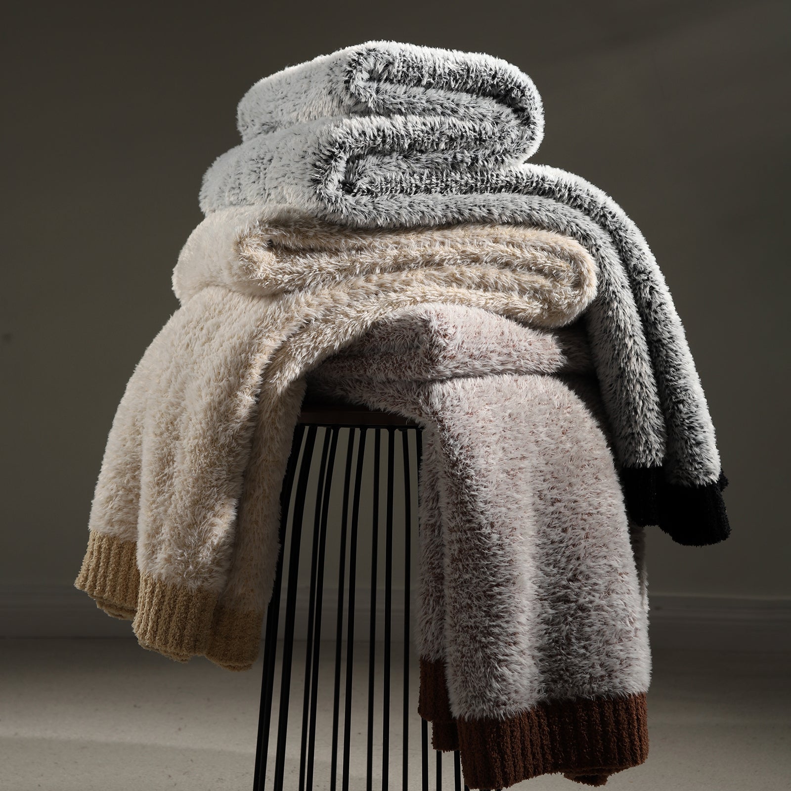 Faux Mink Feather Knit Throw Blanket stacked with different colors, showcasing multiple color options and soft texture.
